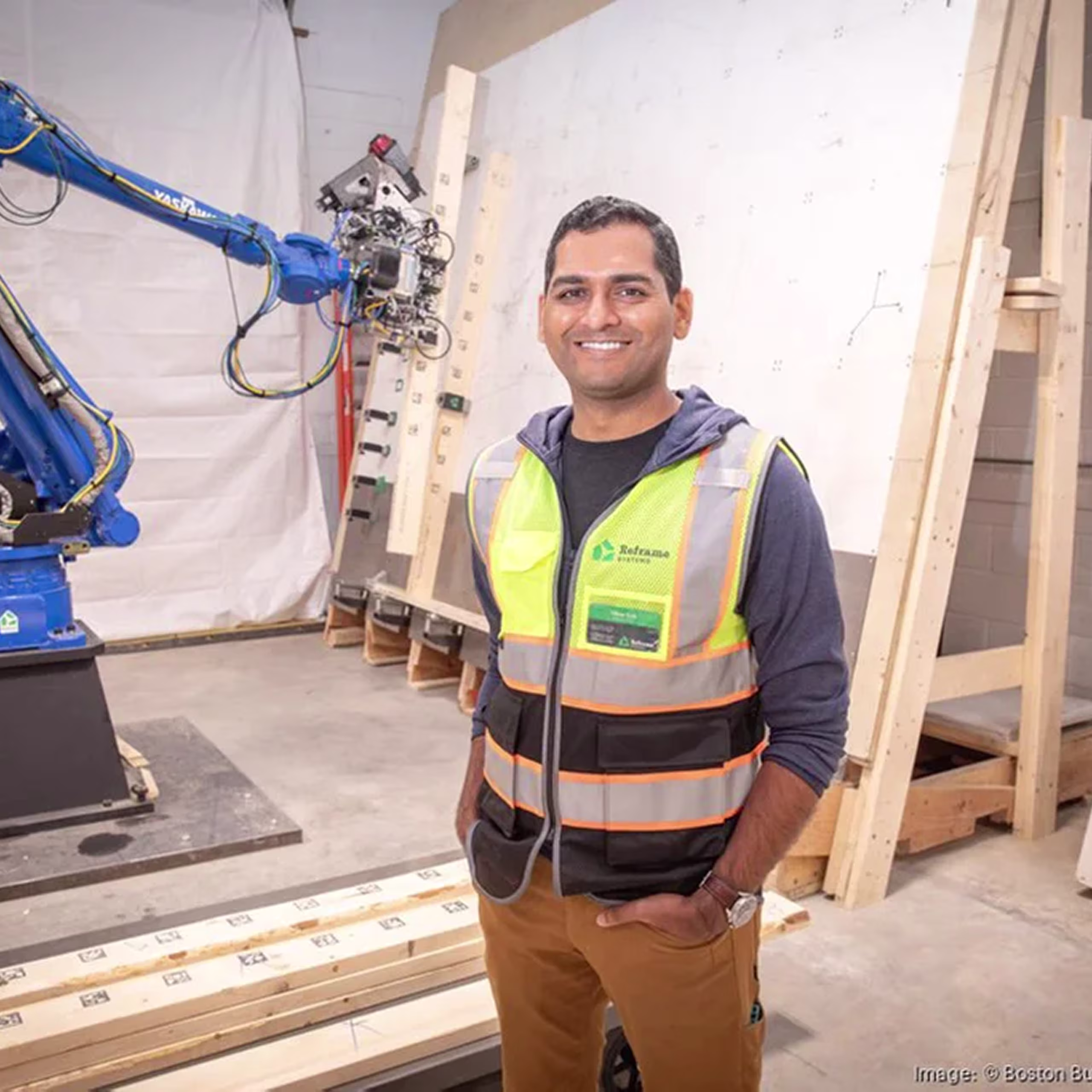 Reframe Systems team member beside a large industrial robotic arm in the workshop