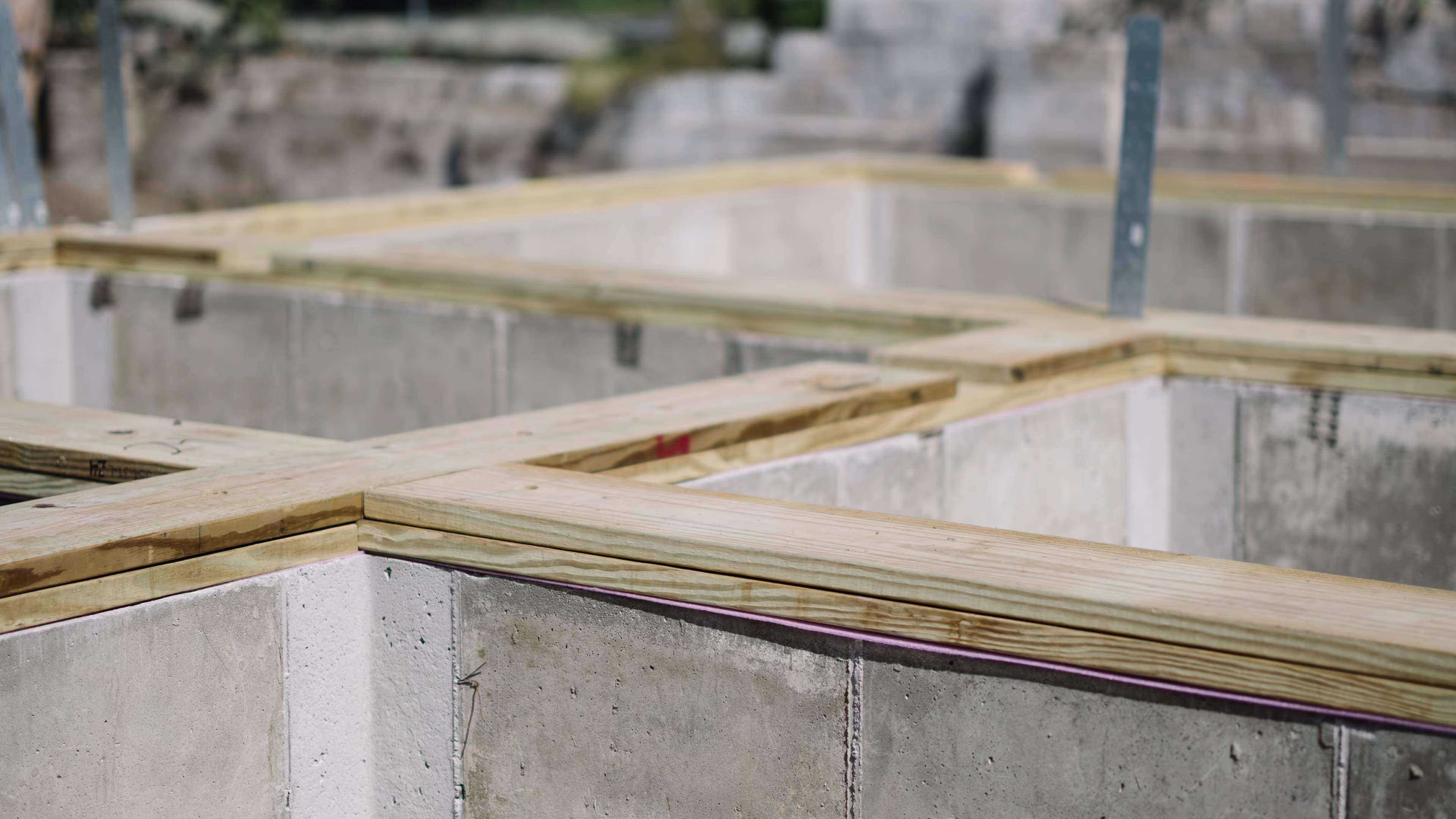 Wooden sill plates laid on a concrete foundation at a modular home site
