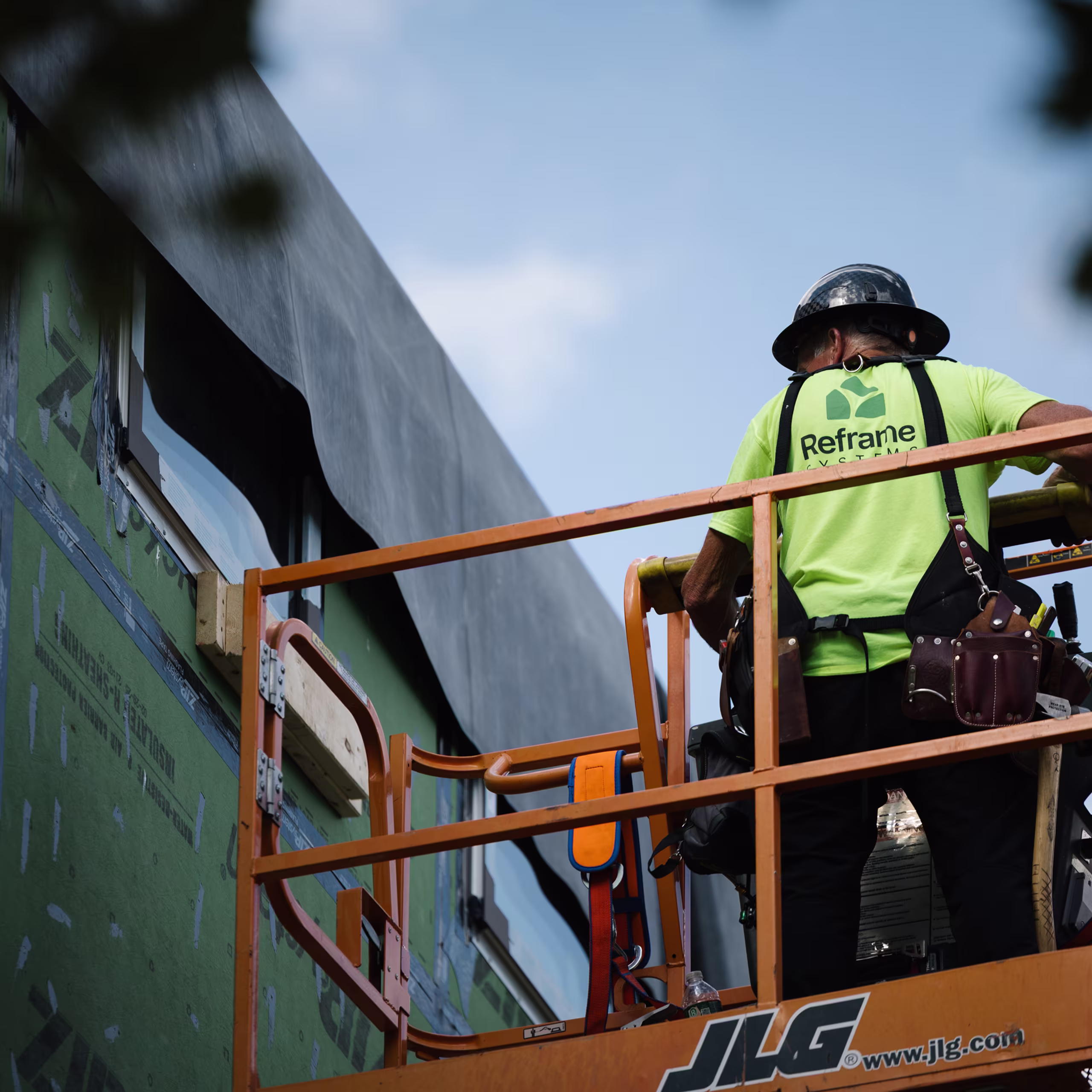 Worker on a boom lift finishing the exterior of a weather-wrapped modular building