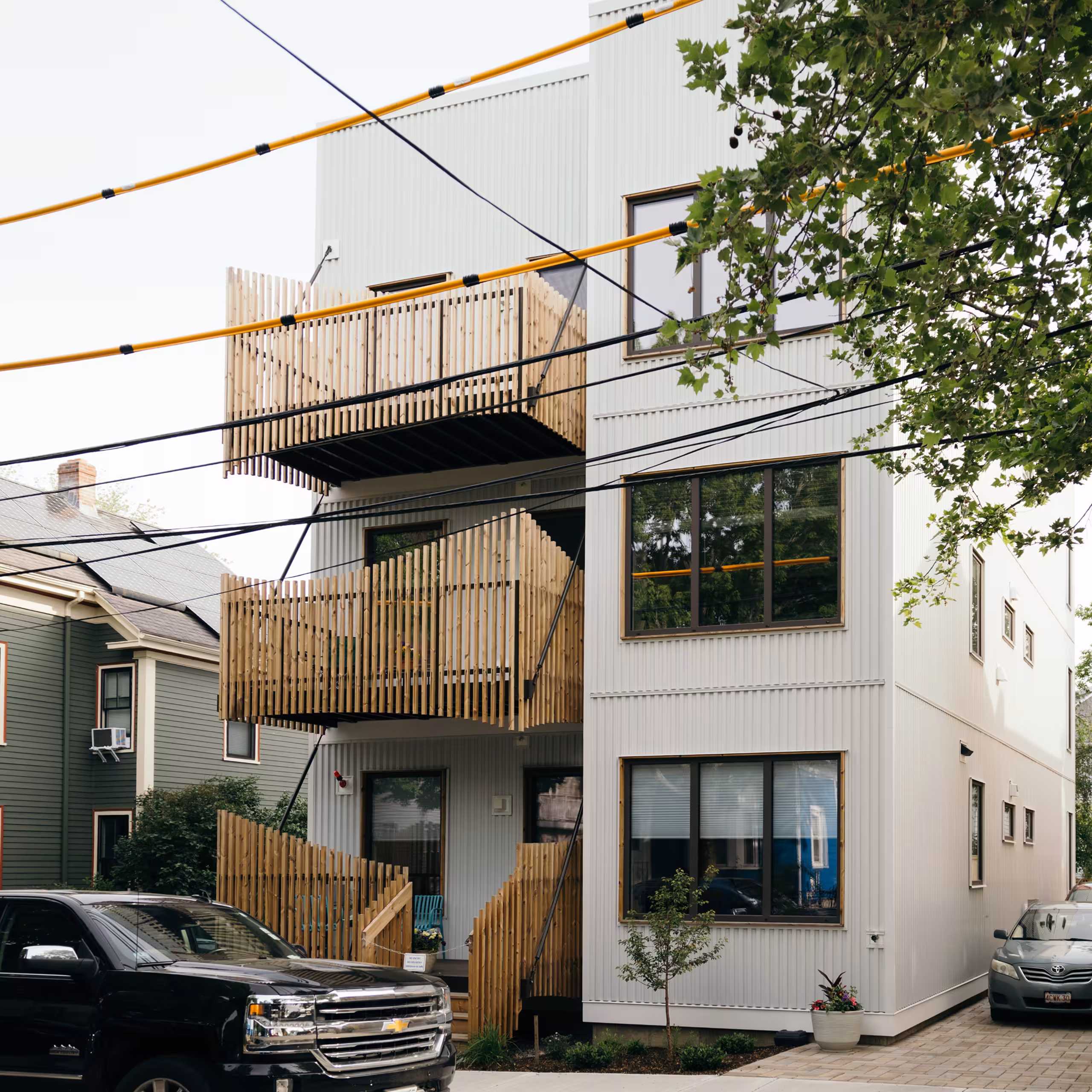 Completed multi-story modular building with wood-railed balconies on a city street