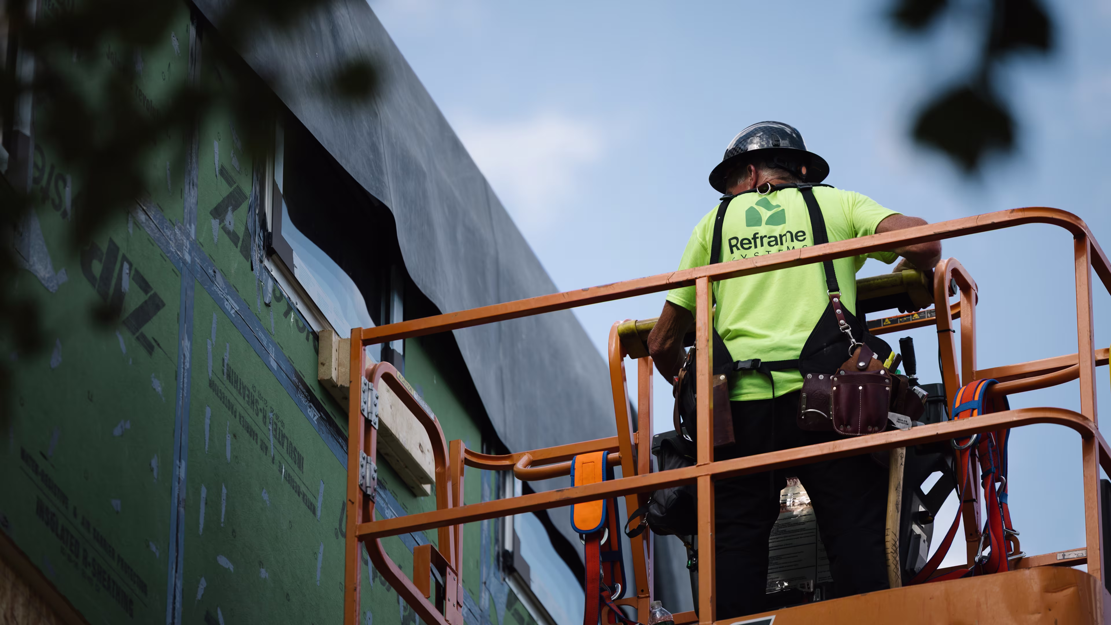 Reframe Systems worker on a boom lift finishing the ZIP-sheathed exterior of a building