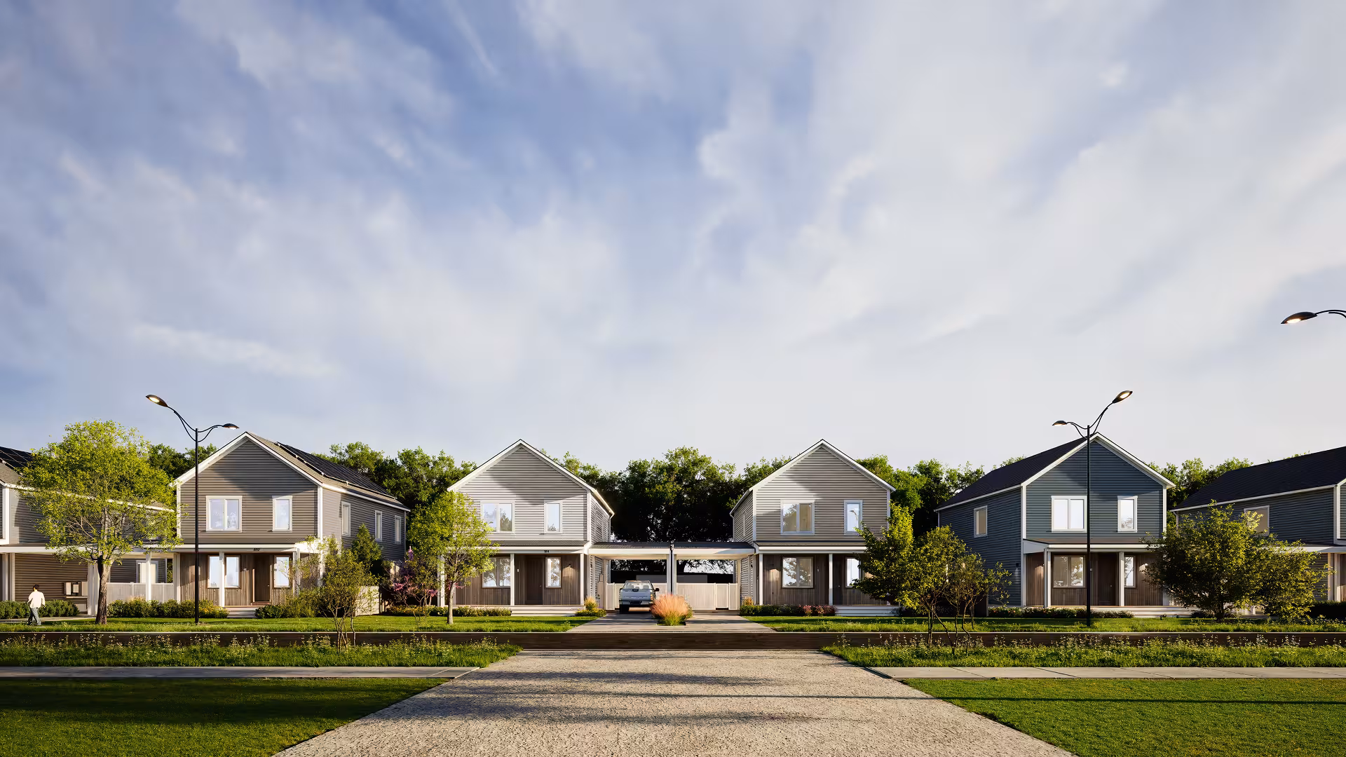 Architectural rendering of a Reframe Systems modular housing development showing a row of two-story homes with varied siding colors, covered porches, and mature landscaping along a residential street