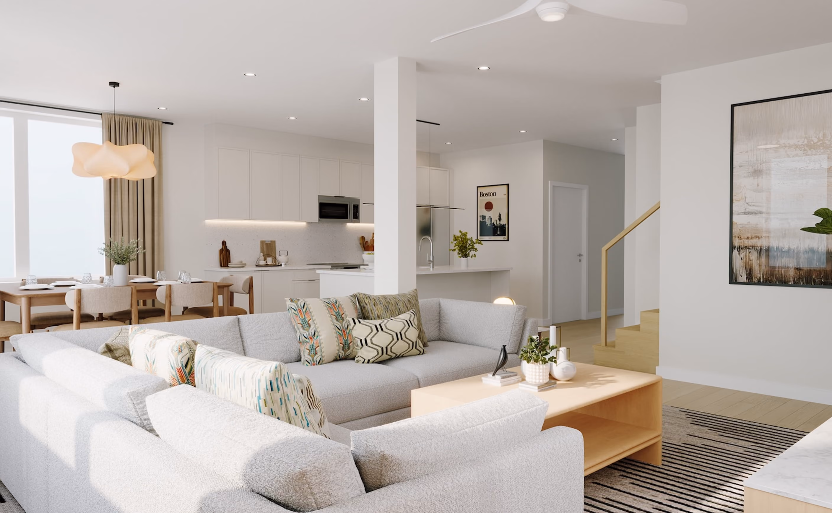 Open-concept living space with a white sectional sofa, wood flooring, and views into the kitchen and dining areas.