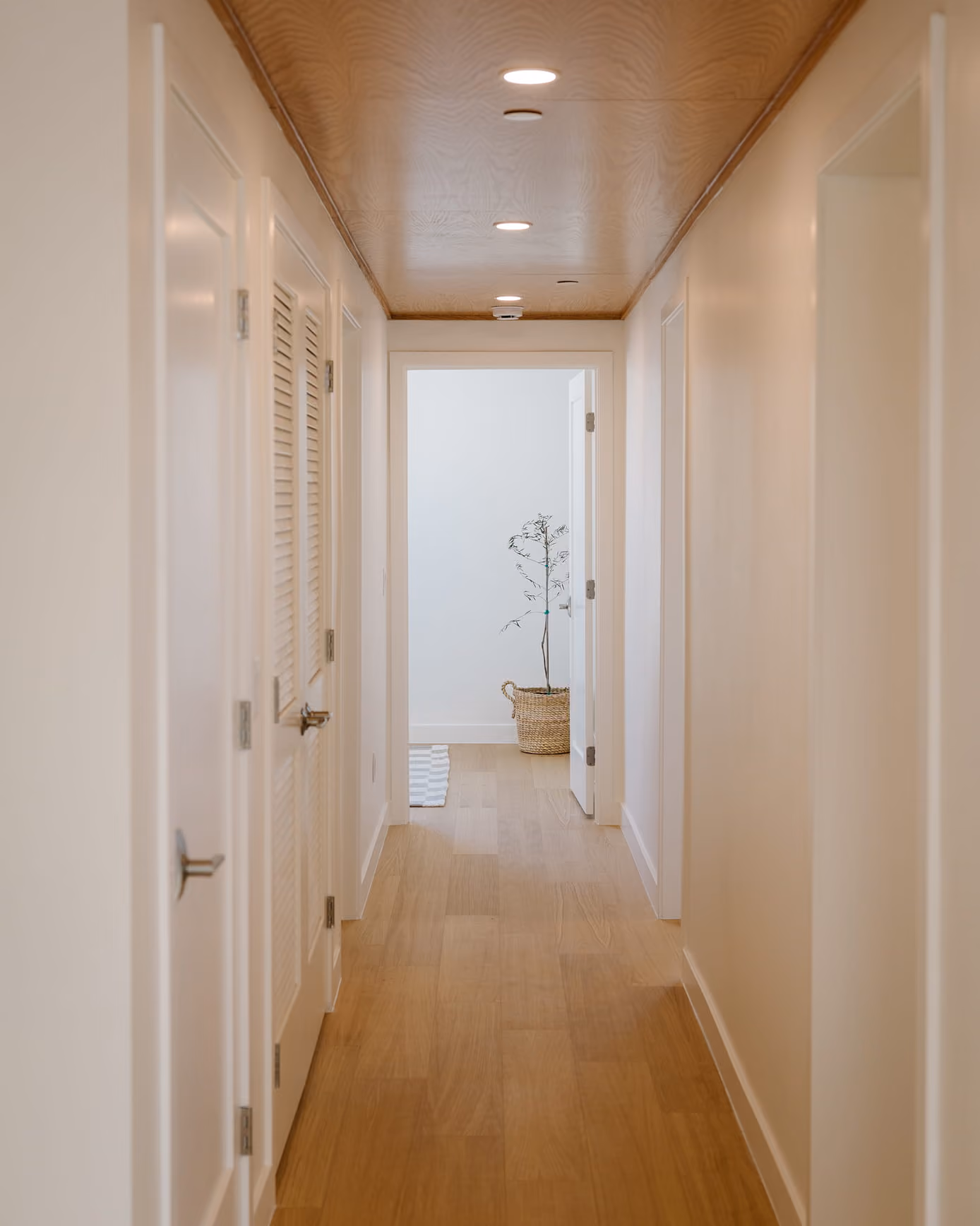 Narrow hallway finished with warm wood paneling and recessed ceiling lights.