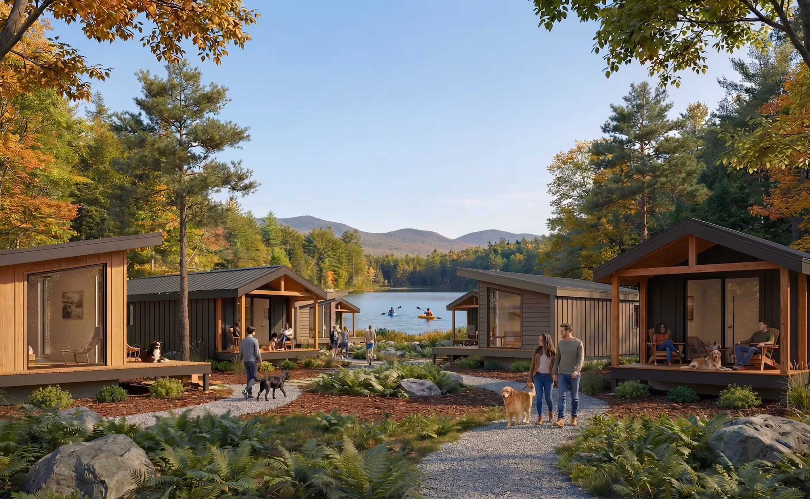 Cluster of modern cabins arranged around landscaped paths beside a lake, with people, dogs, kayakers, and wooded mountains in the distance.