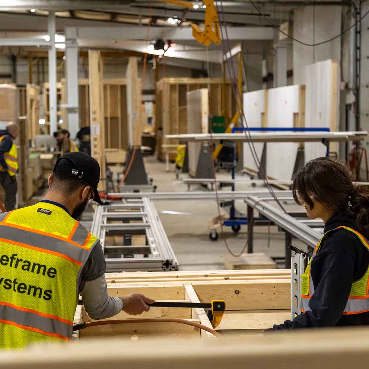 Construction workers assembling wooden framing in a factory