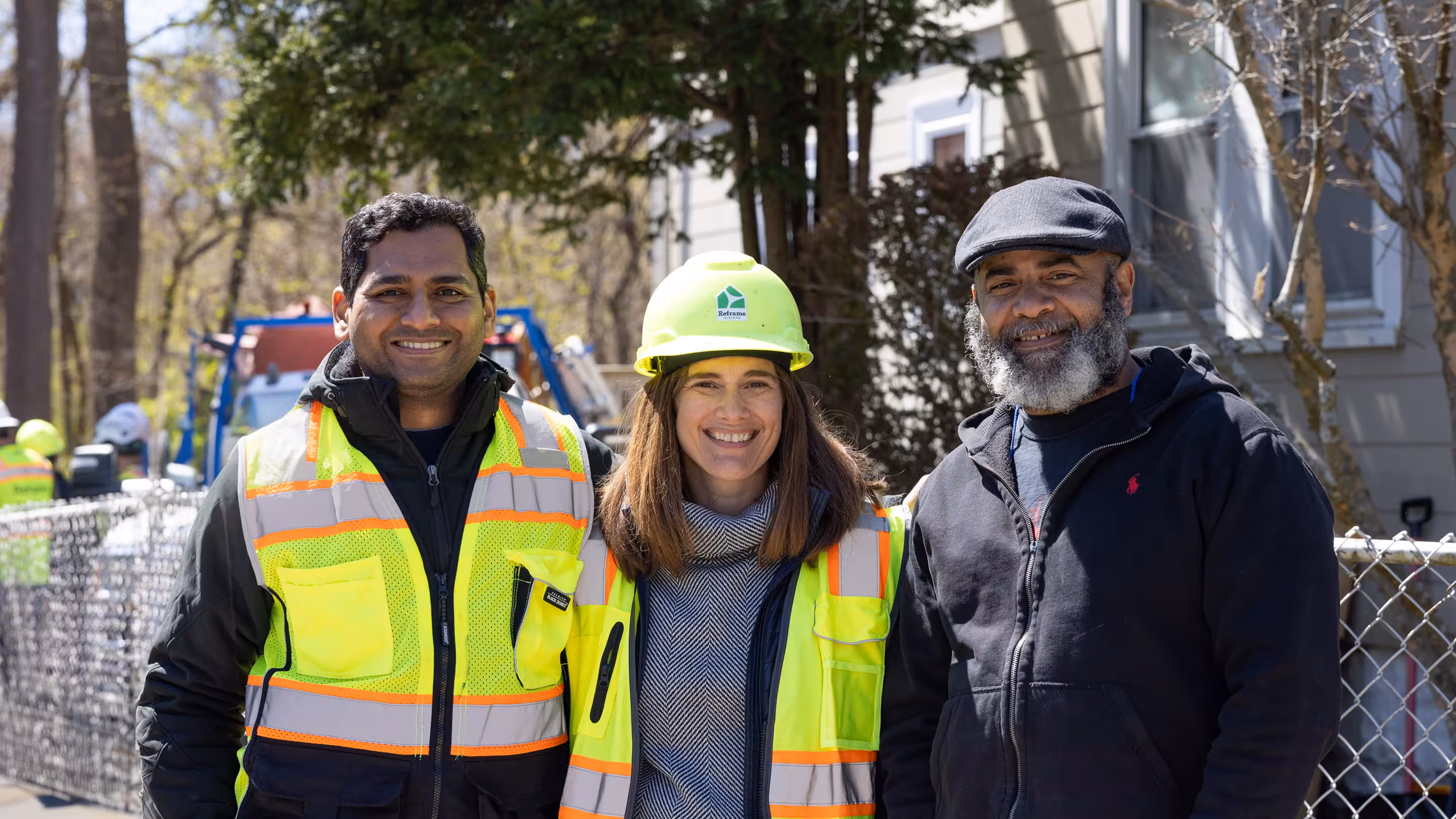 Three people wearing safety vests and hard hats at a construction site