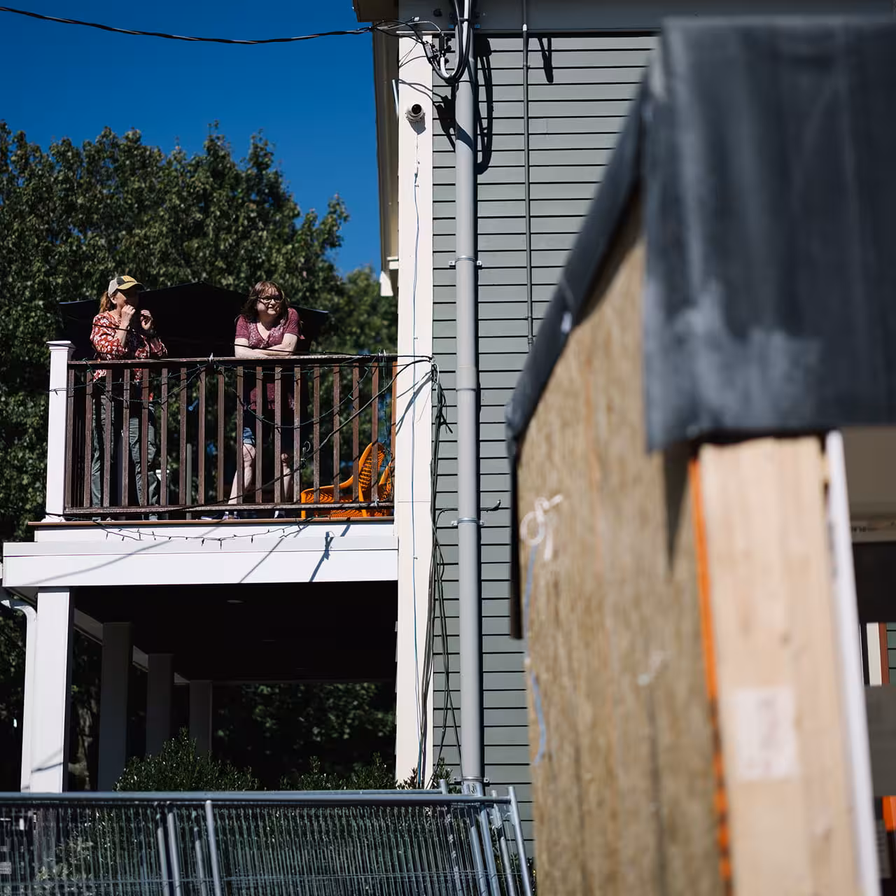 Modular home exterior with workers on the upper balcony