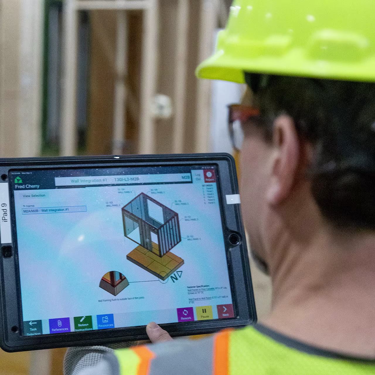 Factory worker reviewing 3D building plans on a computer