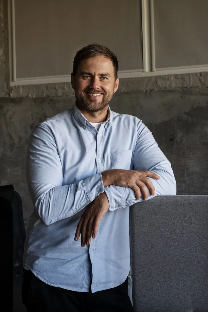 A man in a blue shirt leaning on a table.