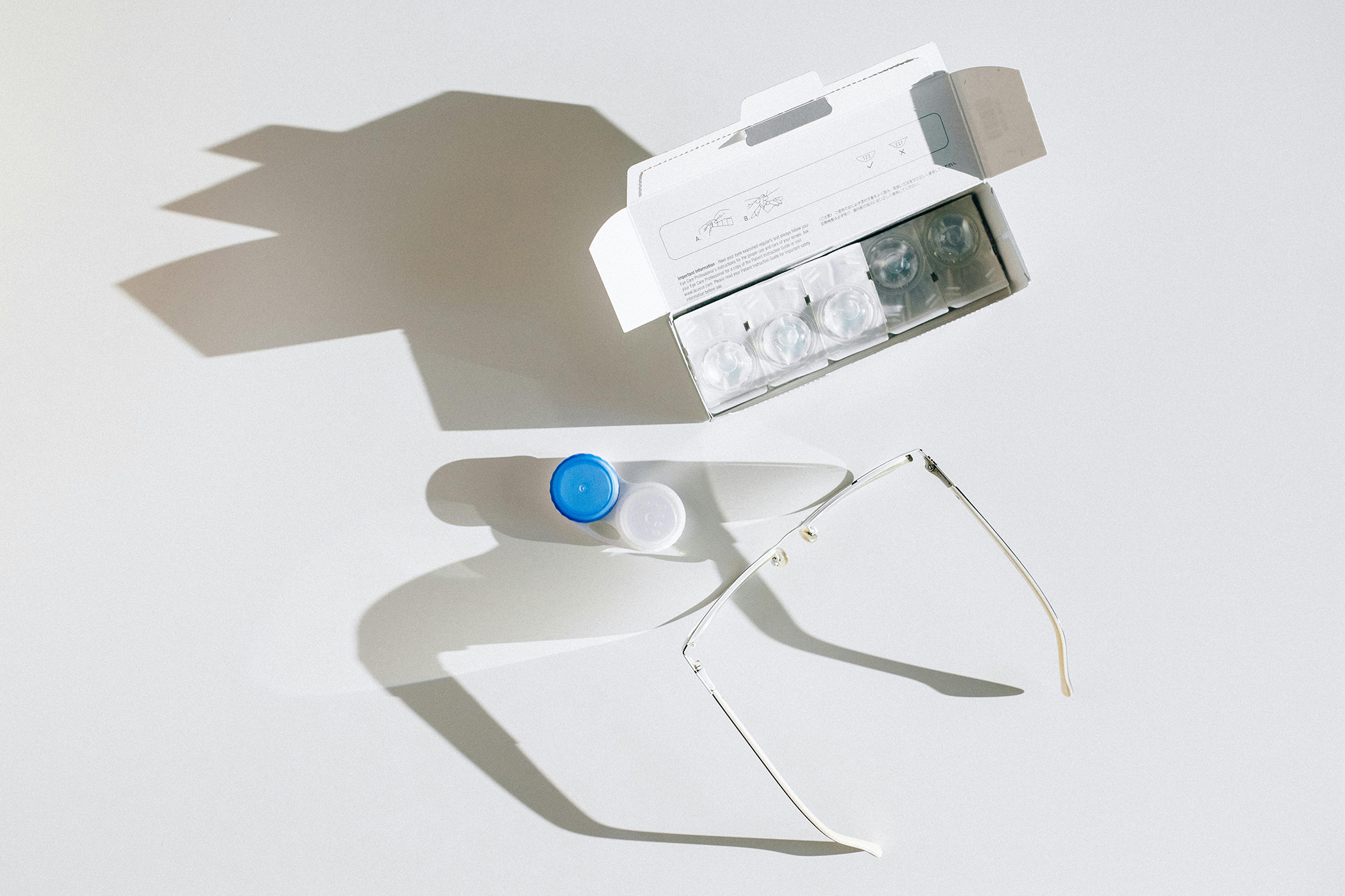Contact lens case, solution bottle, and eyeglasses on white background