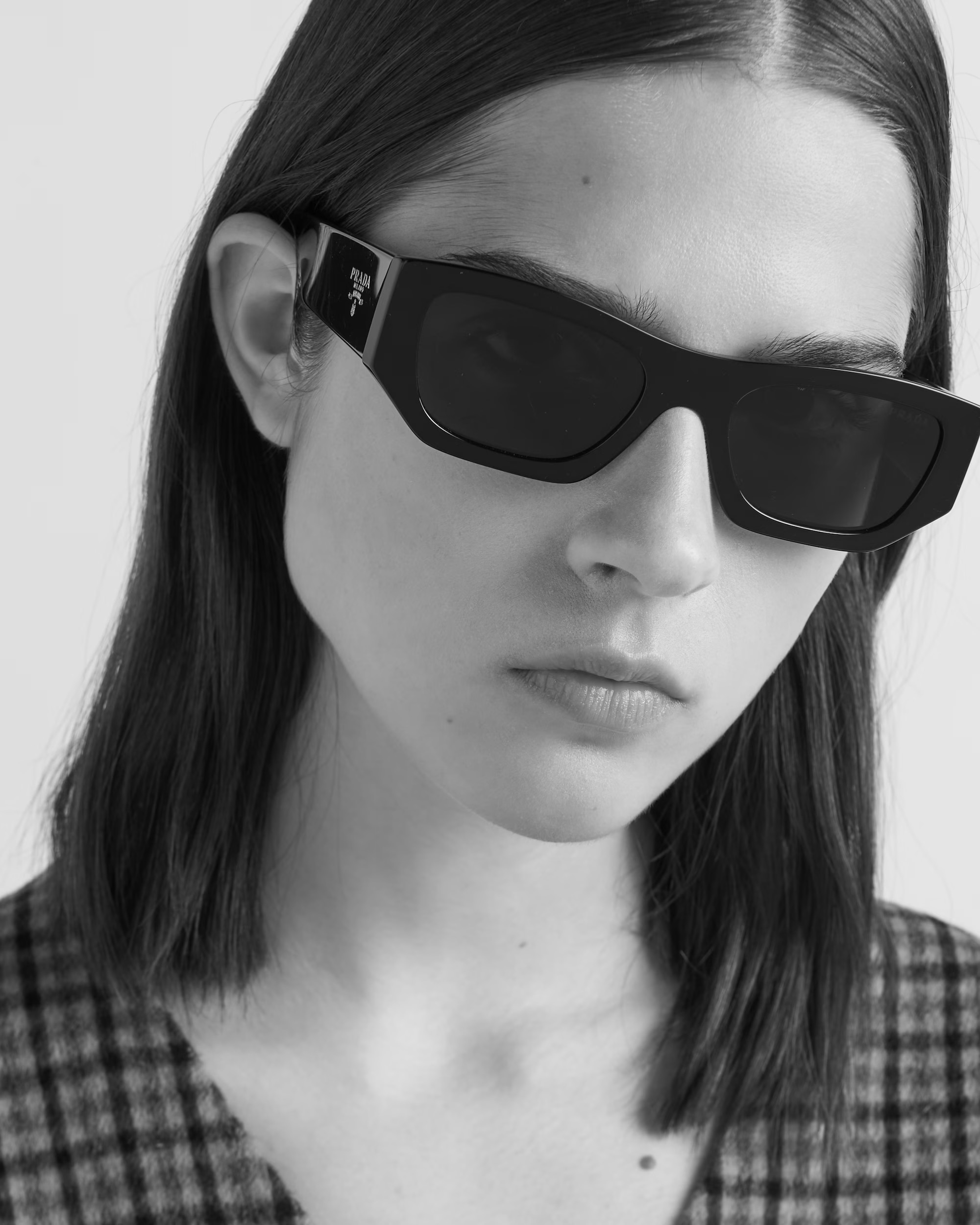 Black and white portrait of a person wearing Prada sunglasses and checkered top
