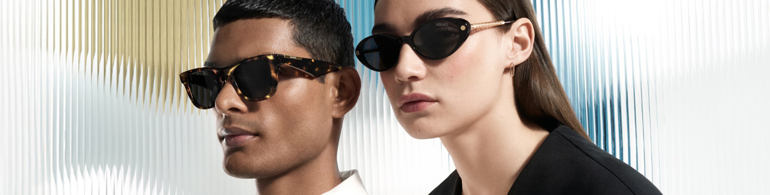 Two models wearing stylish sunglasses against a striped background