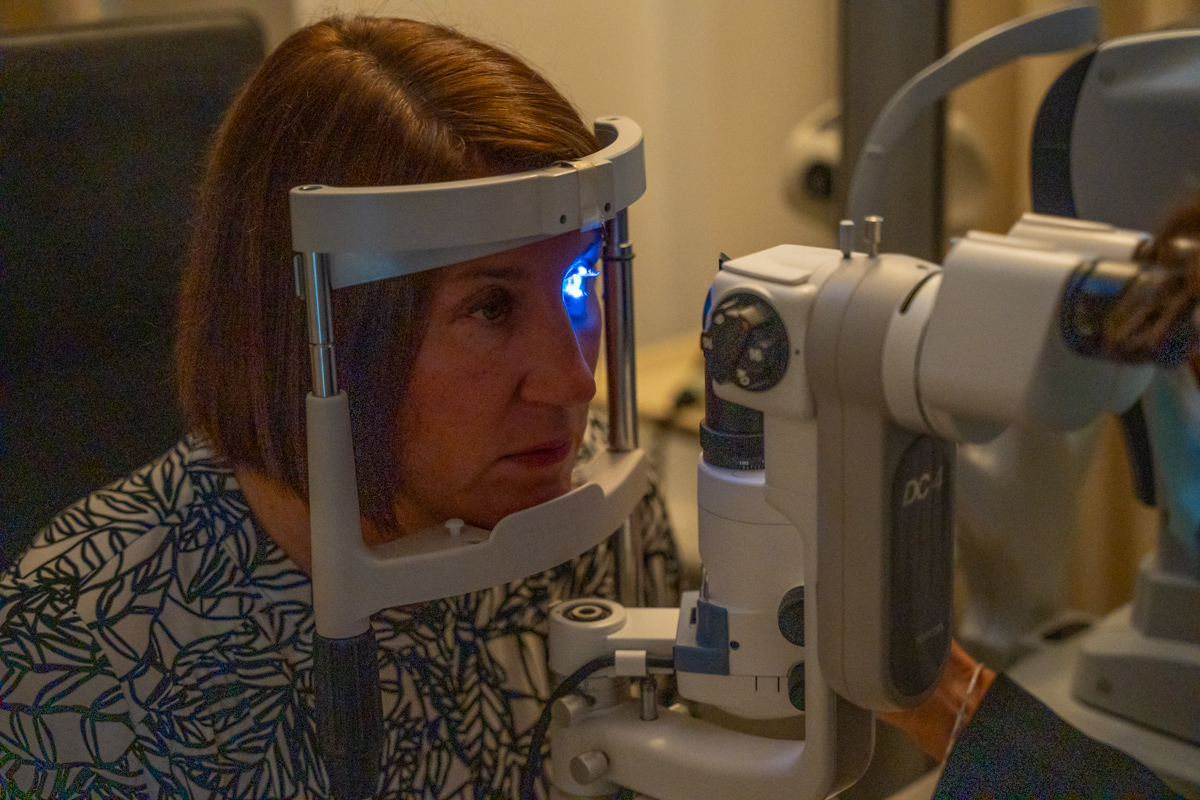 Patient receiving eye exam with blue light ophthalmology equipment