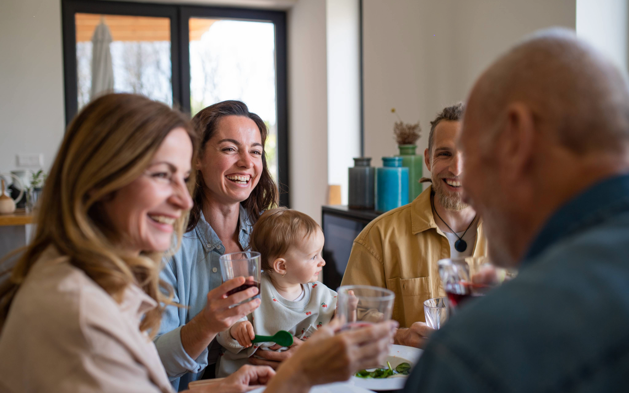 Multigenerational family laughing and enjoying meal together at home