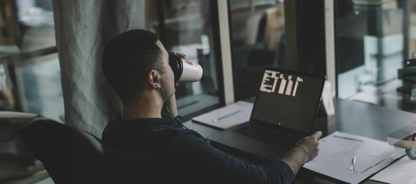 A developer sipping coffee while working on code, symbolizing focus, productivity, and the seamless workflow provided by Alis Exchange’s AI-driven platform for cloud application development.