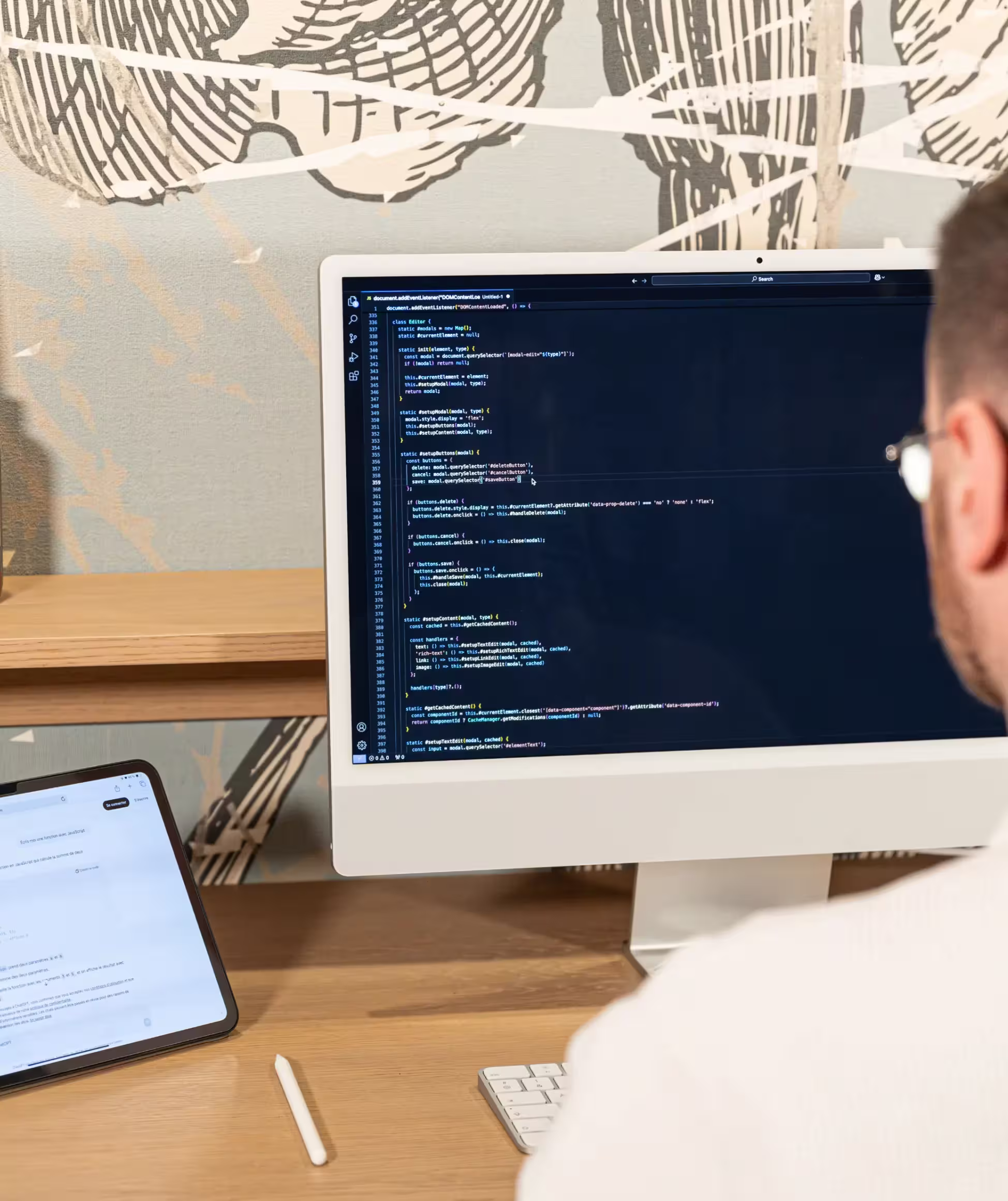 Front-end developers coding on an iMac, with screens displaying lines of colorful code.