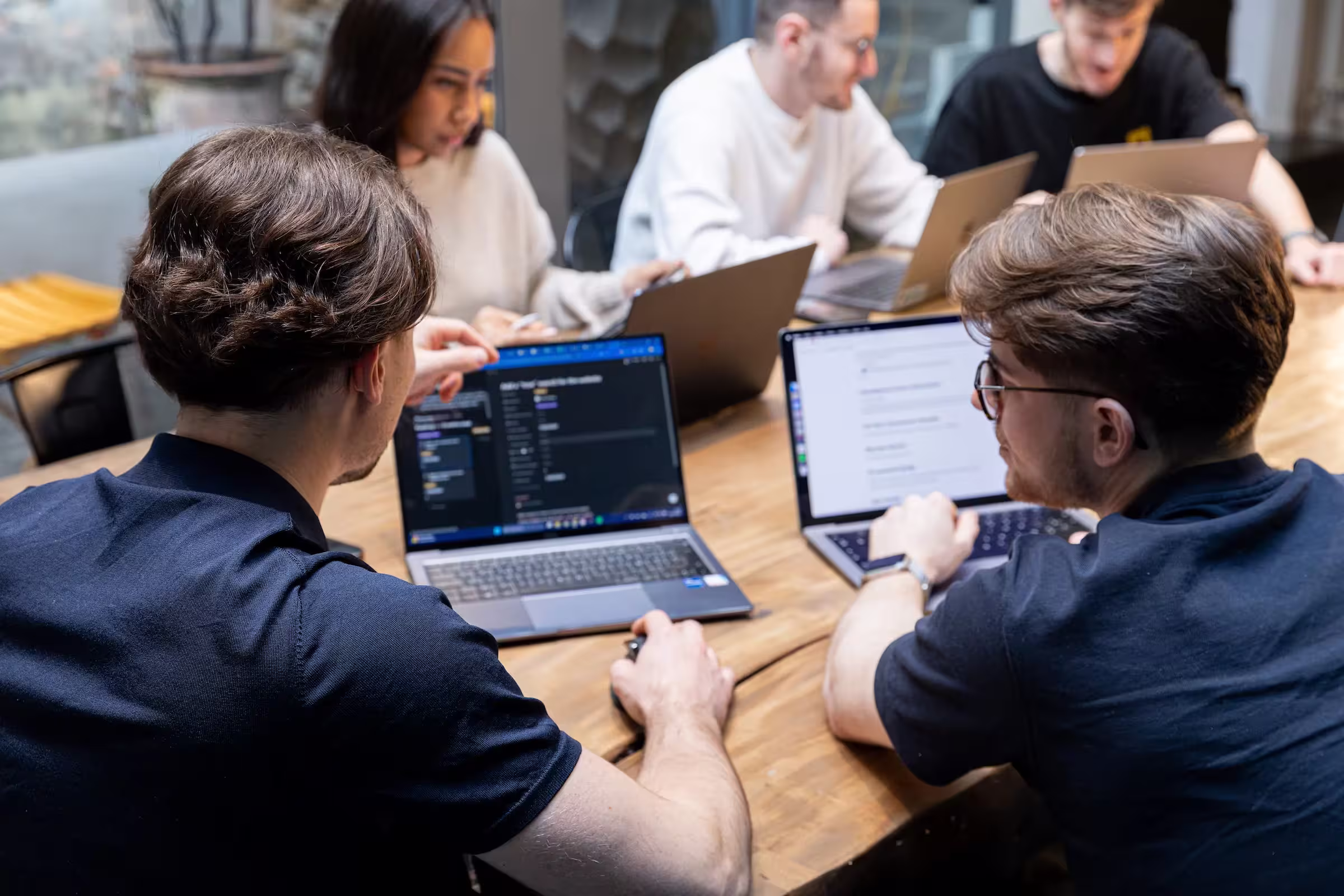 The Digidop team in a collaborative work session around a table, working on their laptops.
