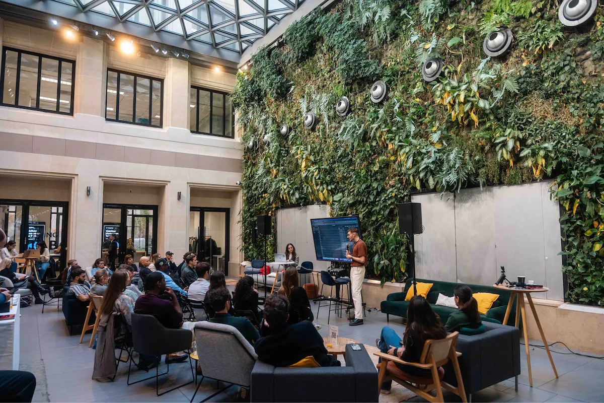 Salle événementielle avec un mur végétal intérieur, où un intervenant présente devant un public assis.