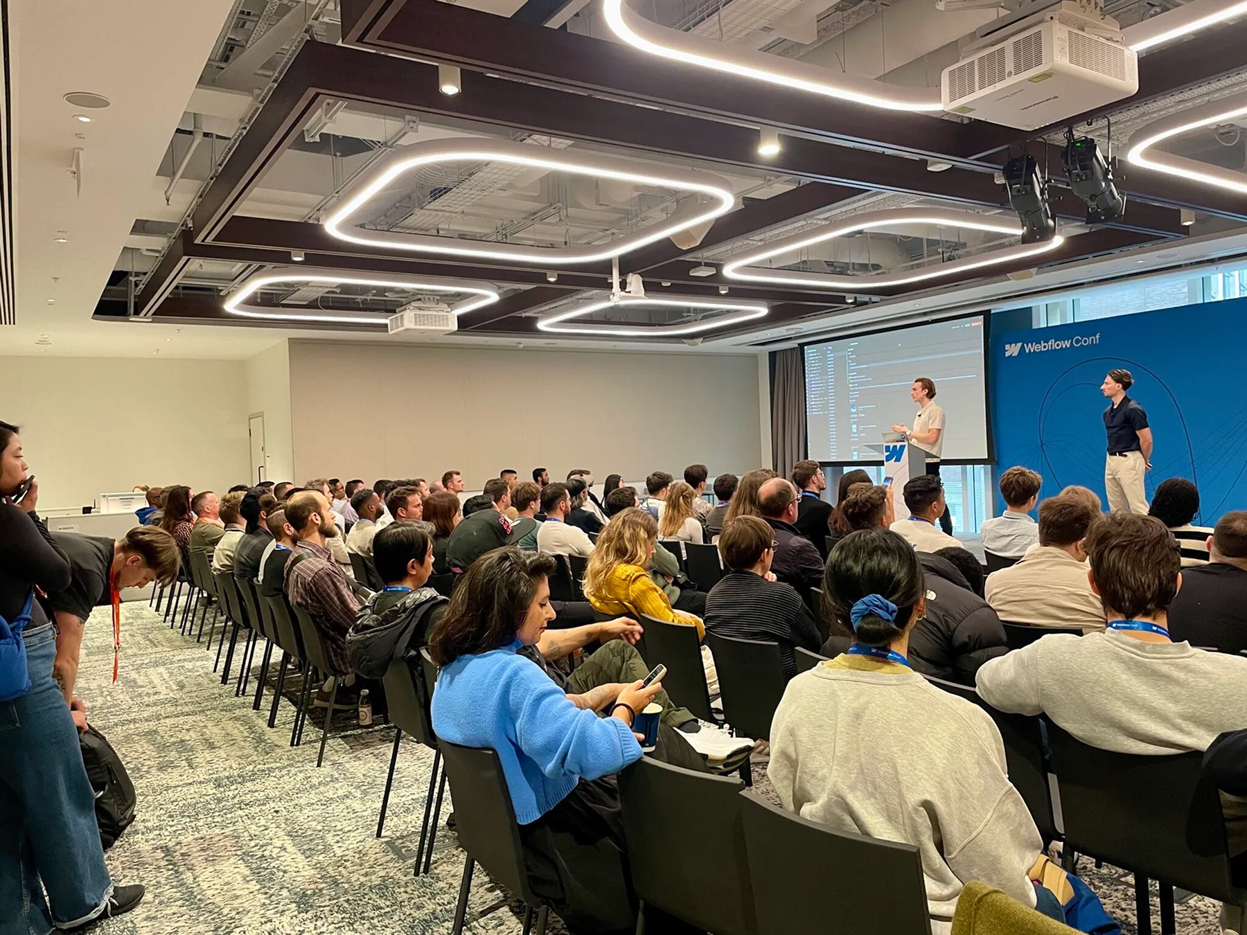 Conférence Webflow devant une salle pleine, avec deux intervenants présentant sur scène.