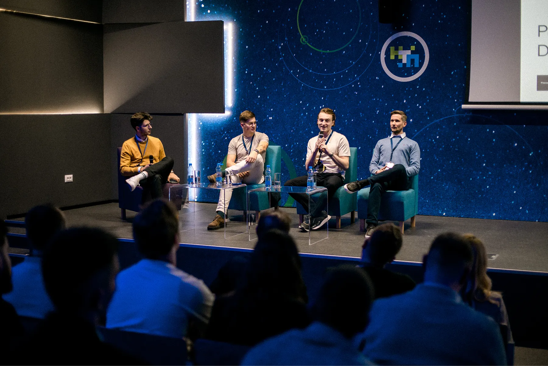 Panel de quatre intervenants sur scène dans un décor bleu, face au public.