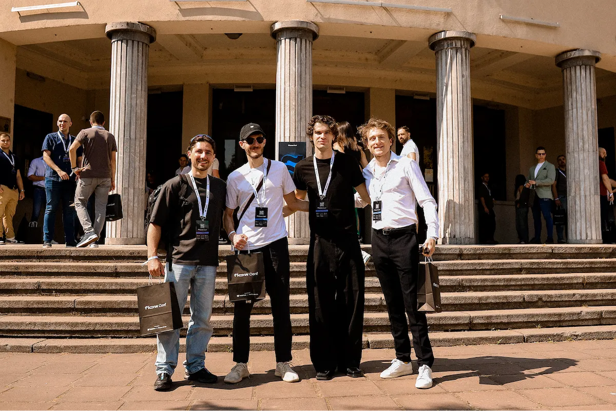 Groupe de participants posant devant l’entrée de FlowConf, badges autour du cou.