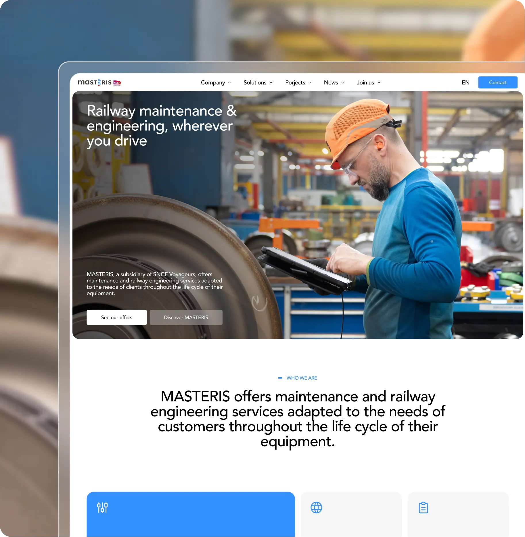 Worker in a factory wearing an orange hard hat and blue shirt uses a tablet for railway equipment maintenance.