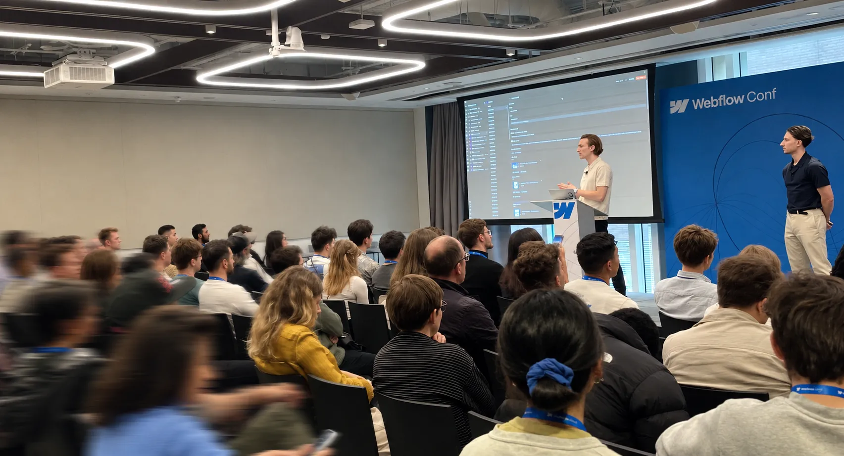 Presentation at Webflow Conf in front of an audience, with a live demonstration of the Webflow interface projected on a large screen.