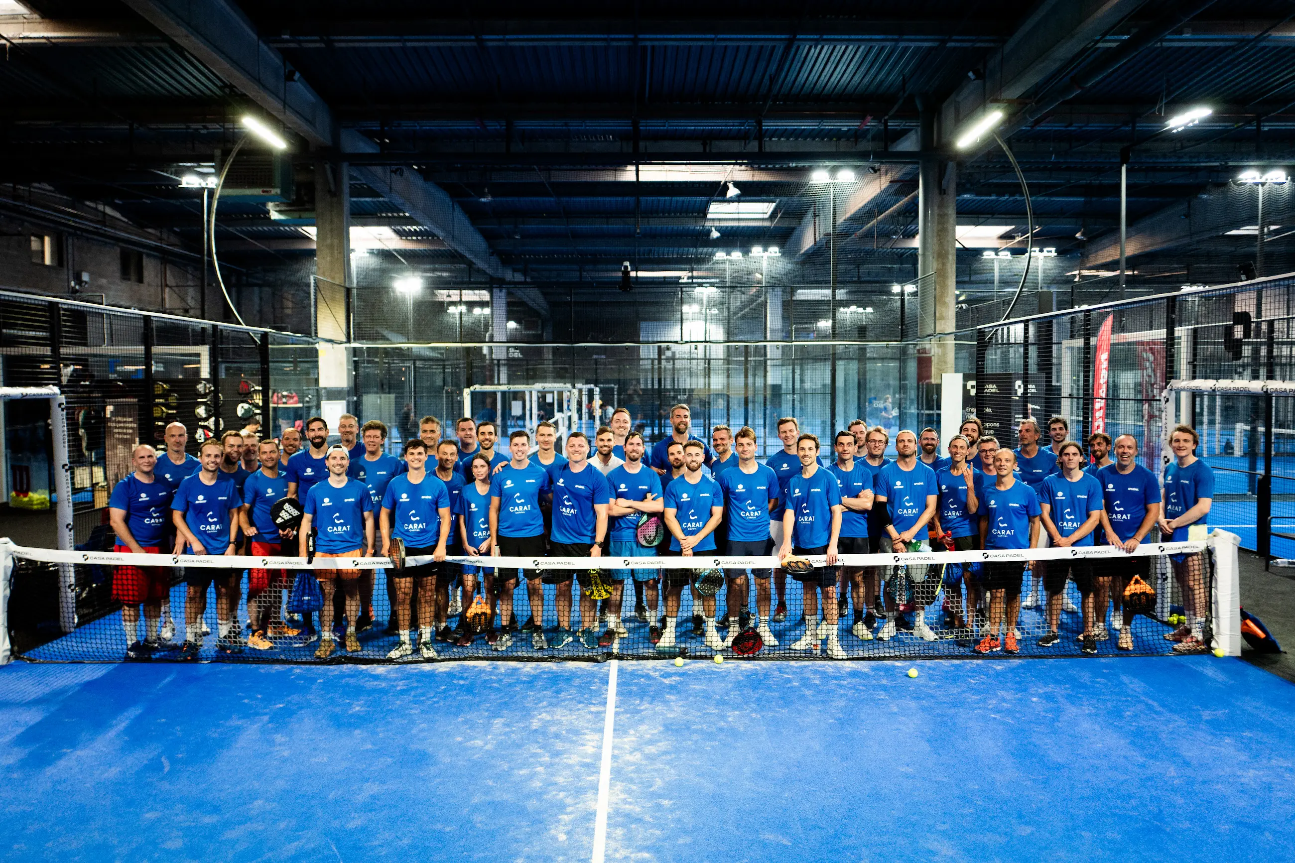 Group photo of Sphère club members on an indoor padel court in Paris.