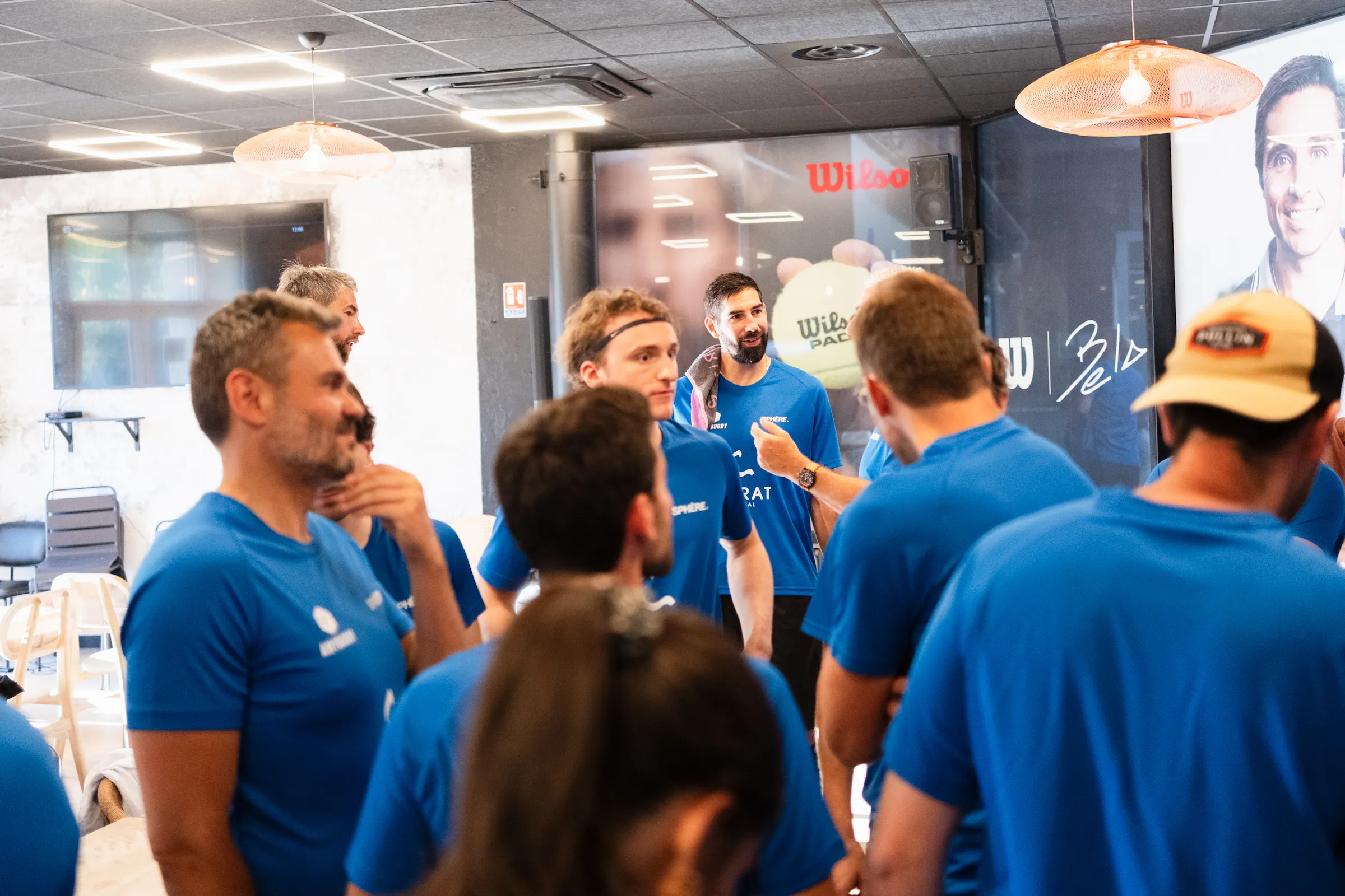 Sphère club members engaged in conversation during an indoor event in Paris, all wearing blue shirts.