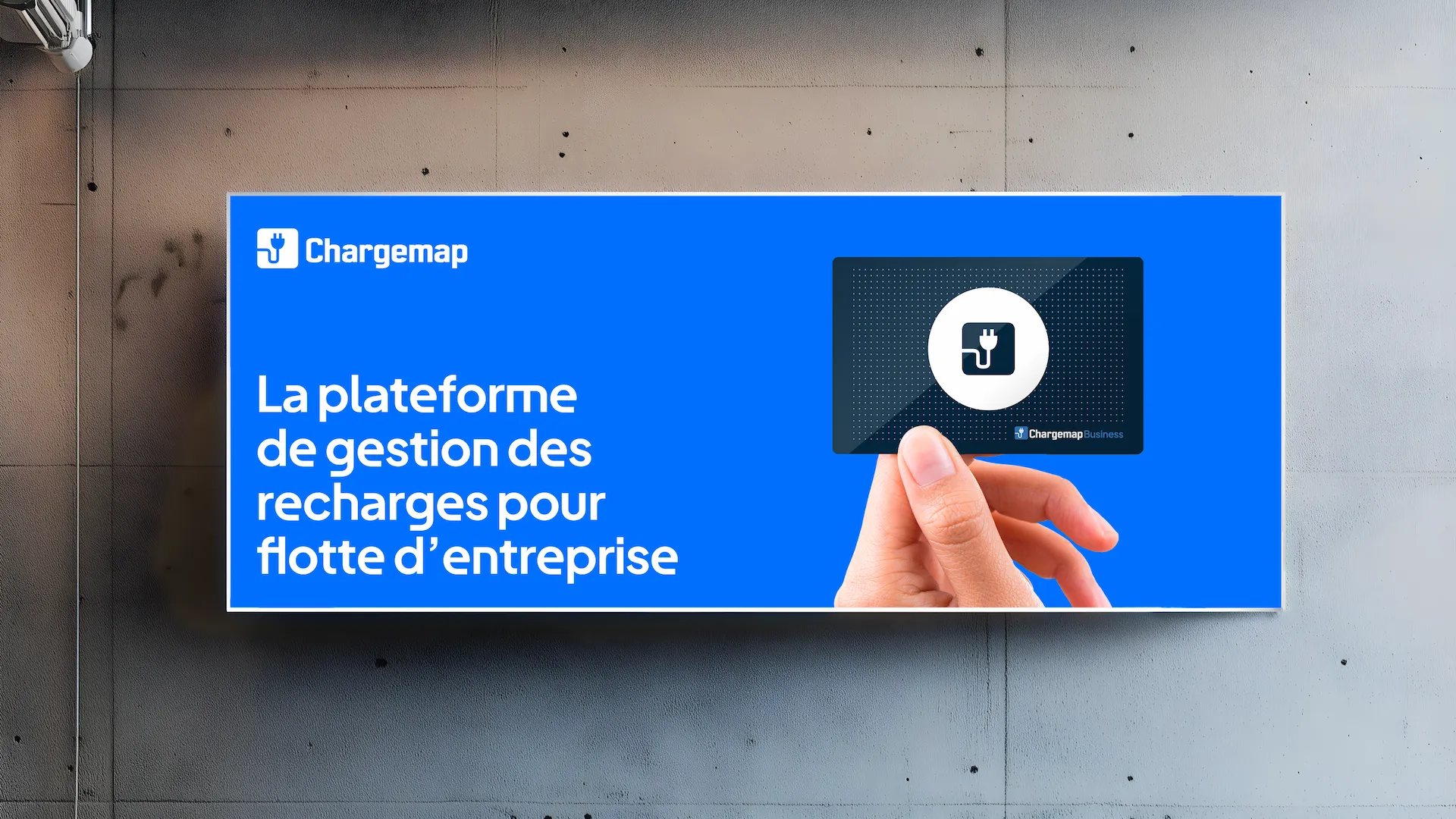 Chargemap Business billboard on concrete wall with charging card in hand.