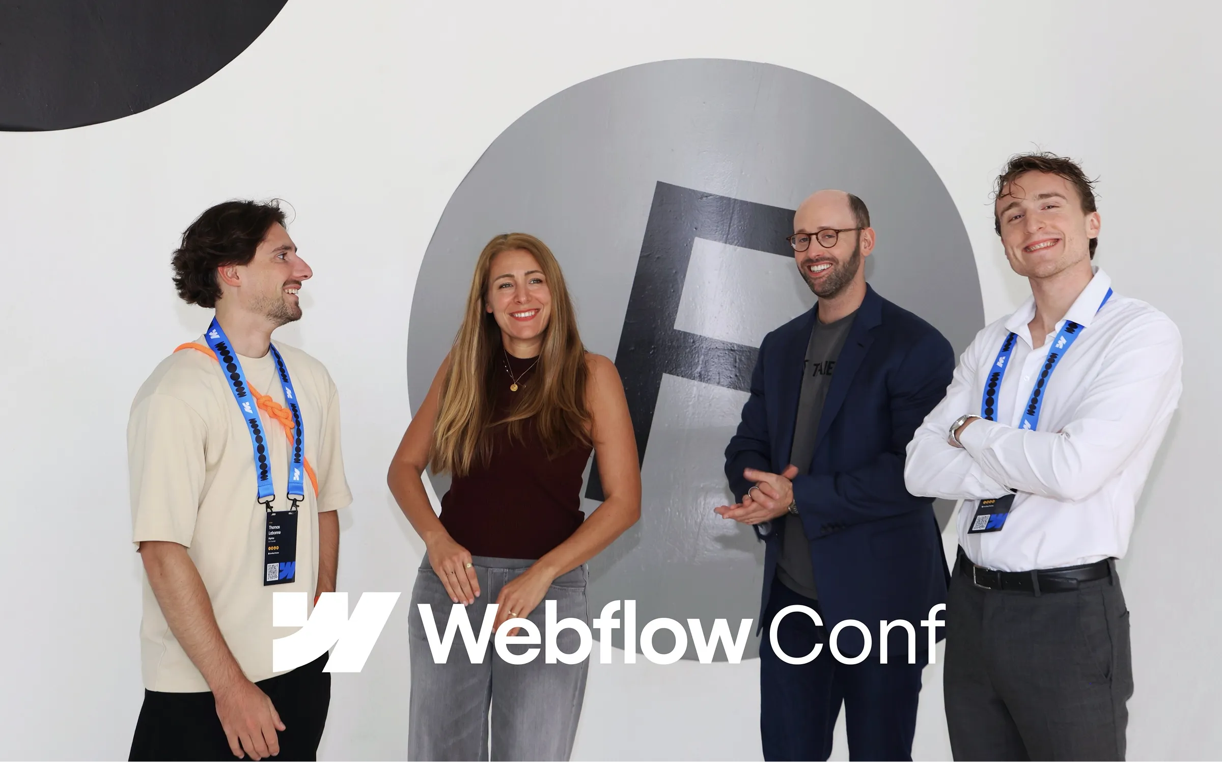 Florian Bodelot, Hélène (Directrice EMEA Webflow), Adrian (CRO Webflow) et Thomas Labonne lors de la Webflow Conf 2025, souriants devant un mur aux lettres graphiques noires et grises.