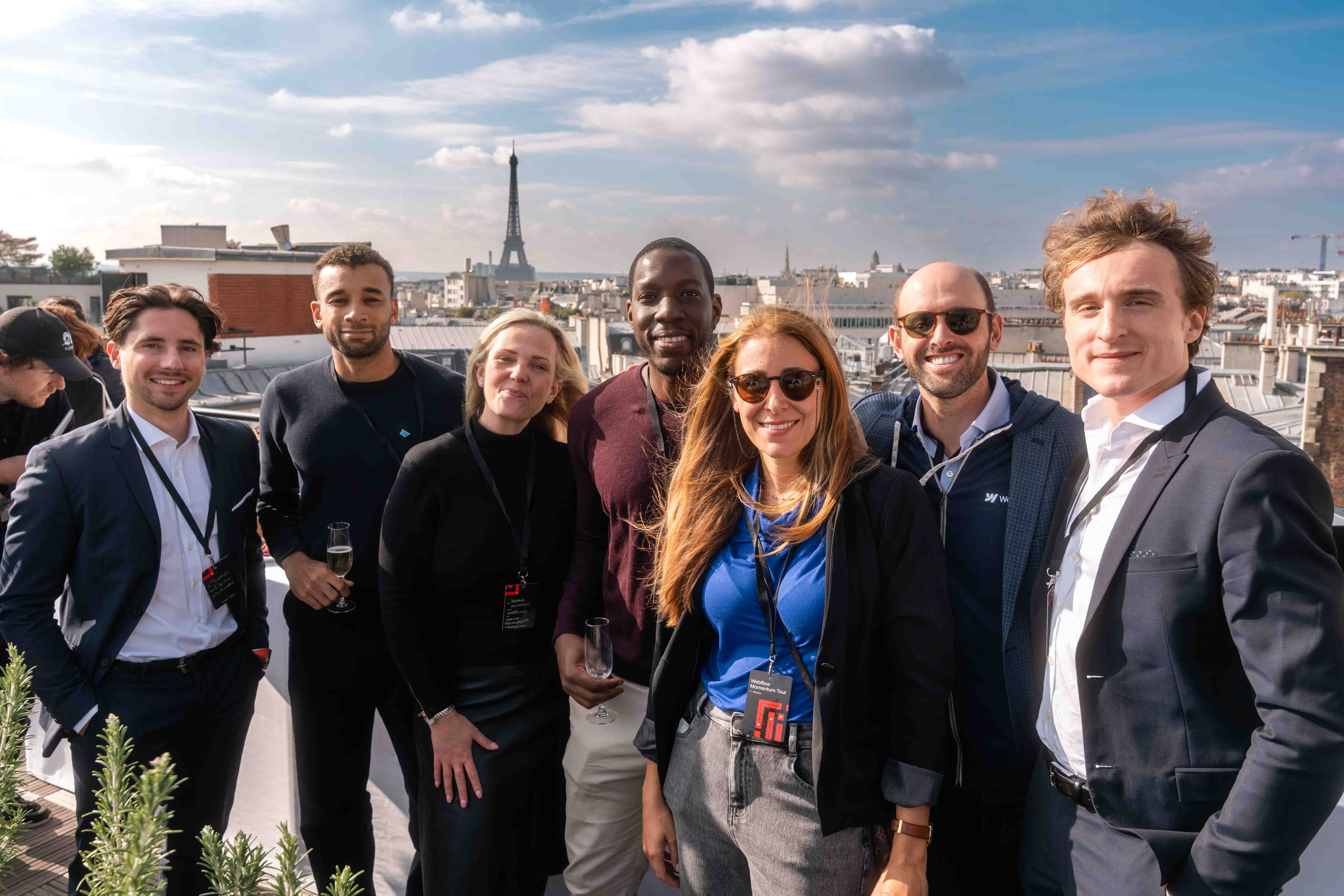 Photo de groupe sur le rooftop du Webflow Momentum Tour Paris avec Hélène, Directrice EMEA chez Webflow, et Thomas et Florian, cofondateurs de Digidop, en compagnie d’autres participants, avec la tour Eiffel en arrière-plan.