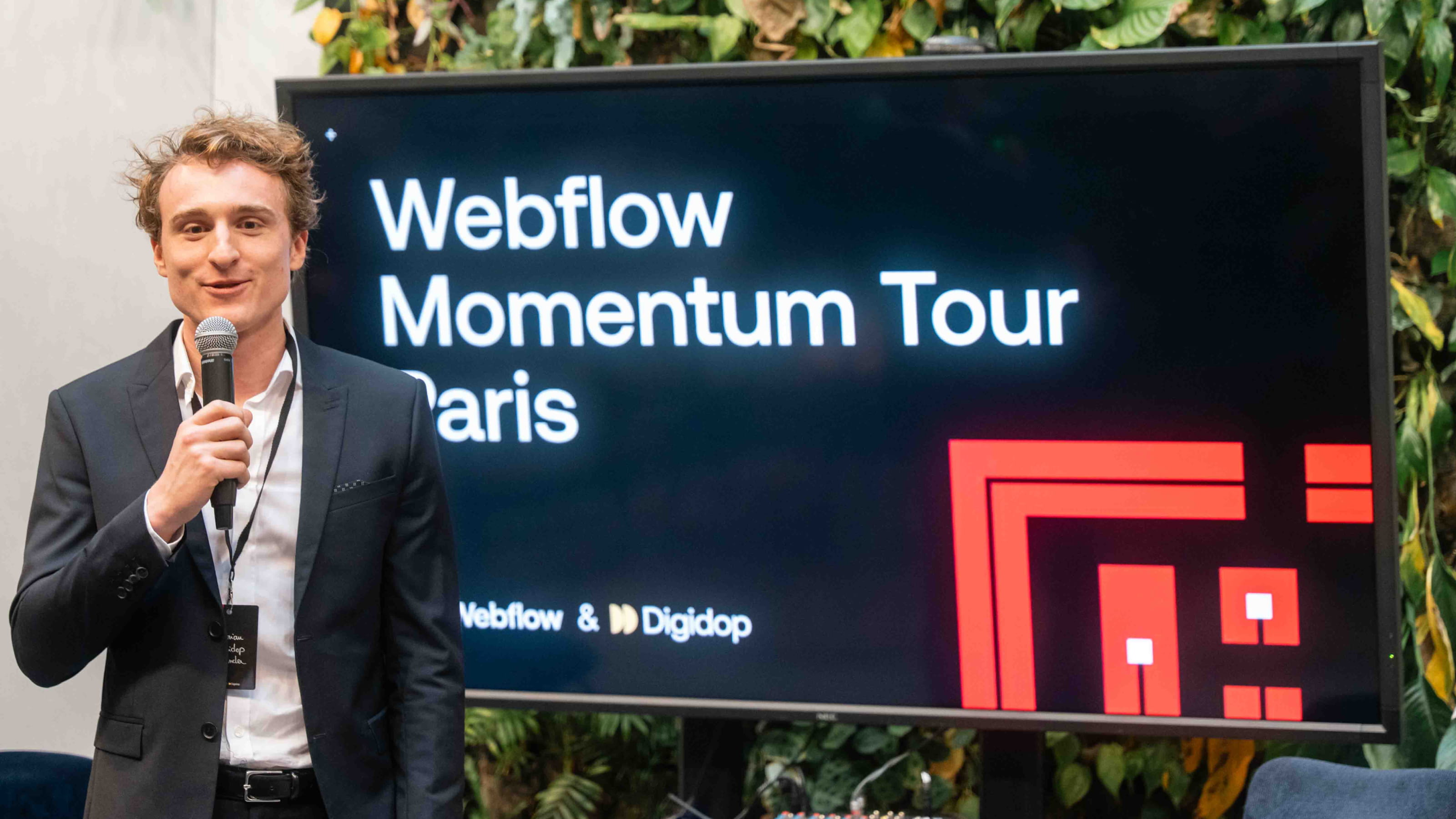 Florian Bodelot Speaker introducing the Webflow Momentum Tour Paris, co-hosted by Webflow and Digidop, in front of a presentation screen.