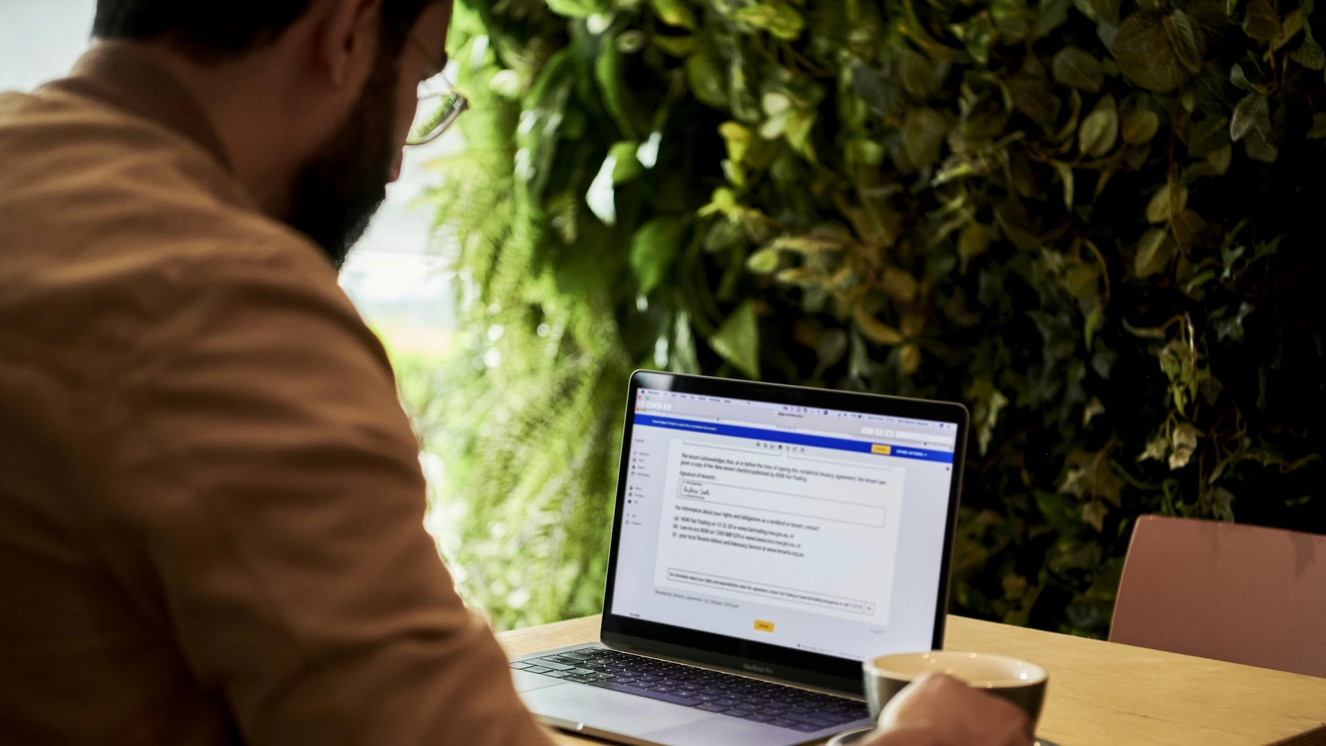 Homme regardant son ordinateur sur un bureau avec un document IDD affiché à l’écran.