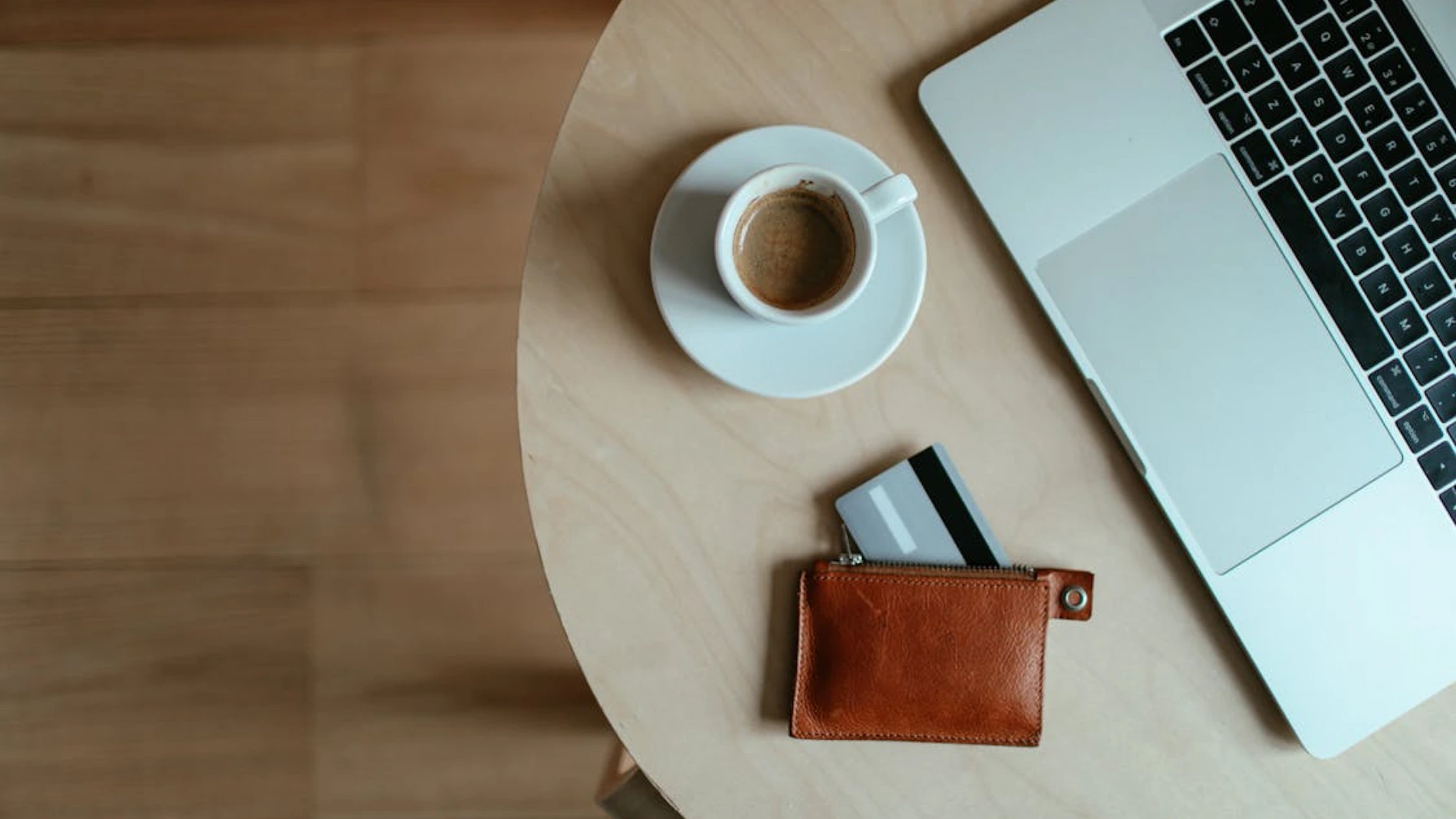 photo of a table with a coffee, a computer, and a wallet with bank cards