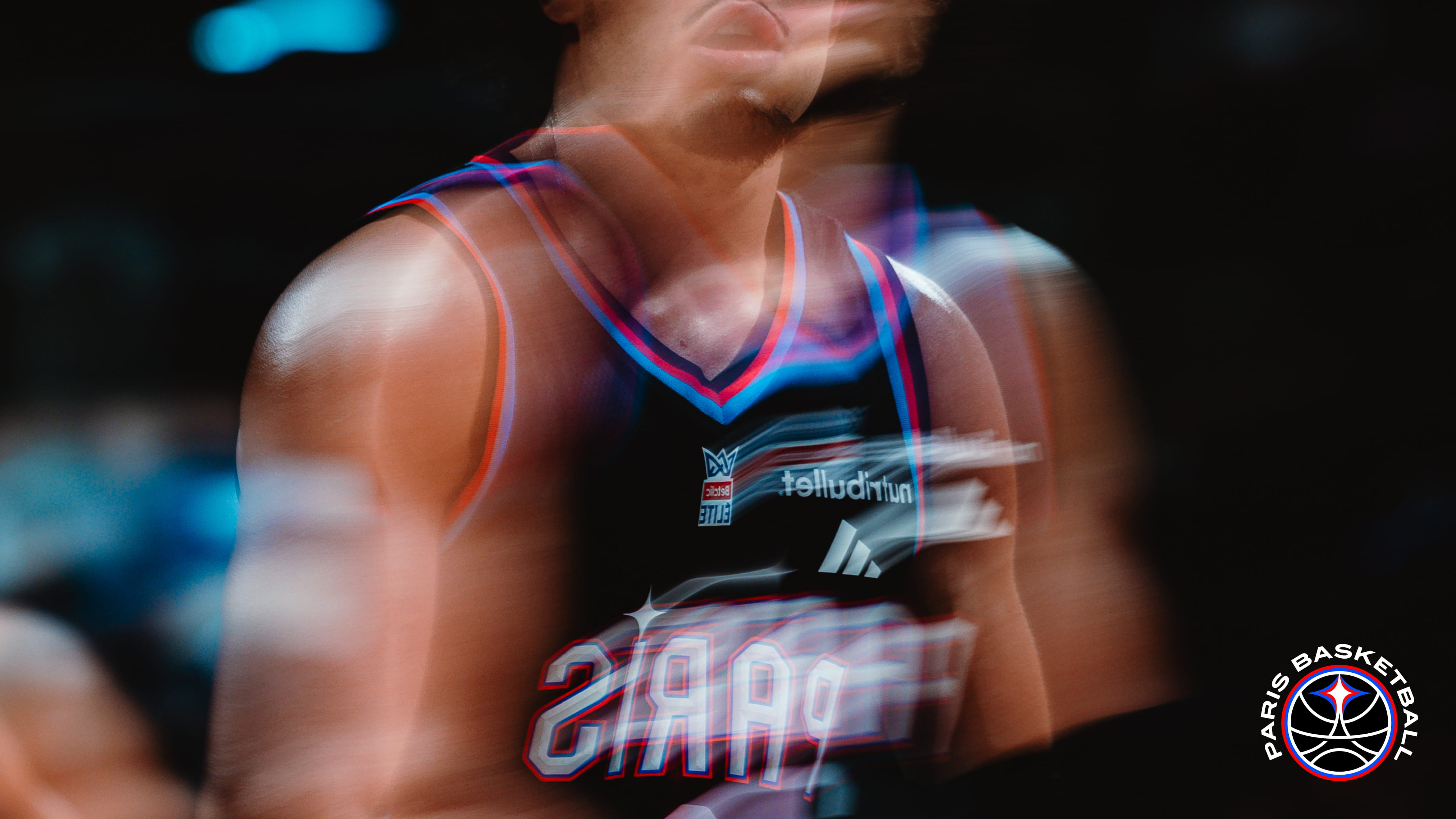 Paris Basketball player captured in motion on the court, with a dynamic motion blur effect during a game.