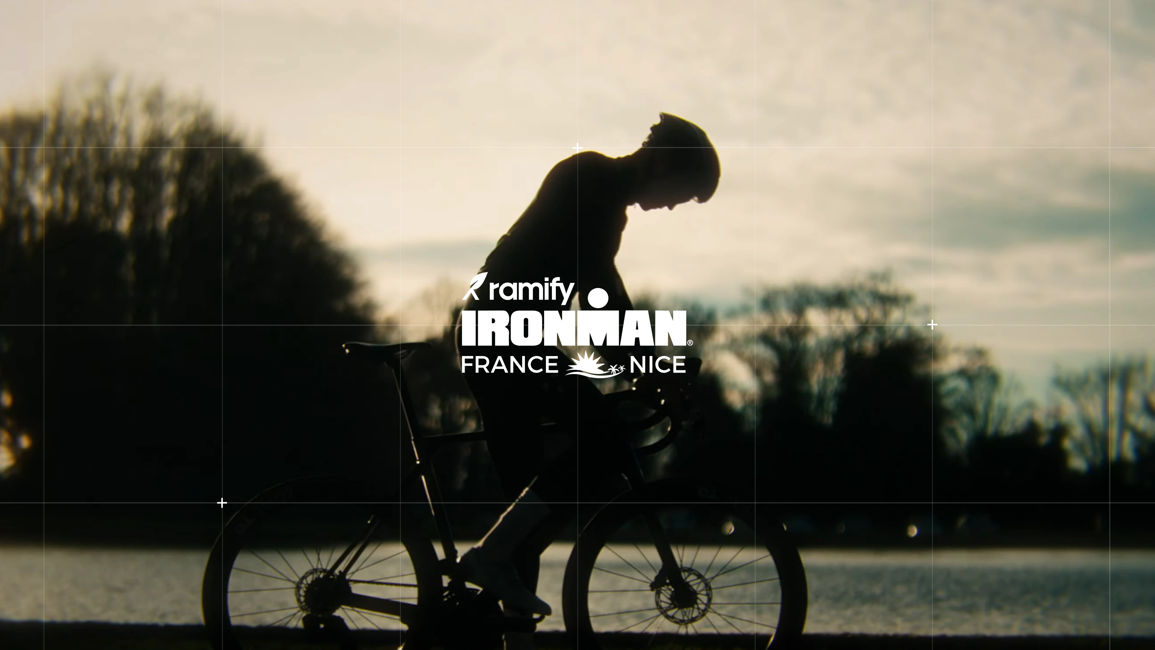 Homme à vélo en arrière-plan, avec le logo Ramify IRONMAN Nice au premier plan