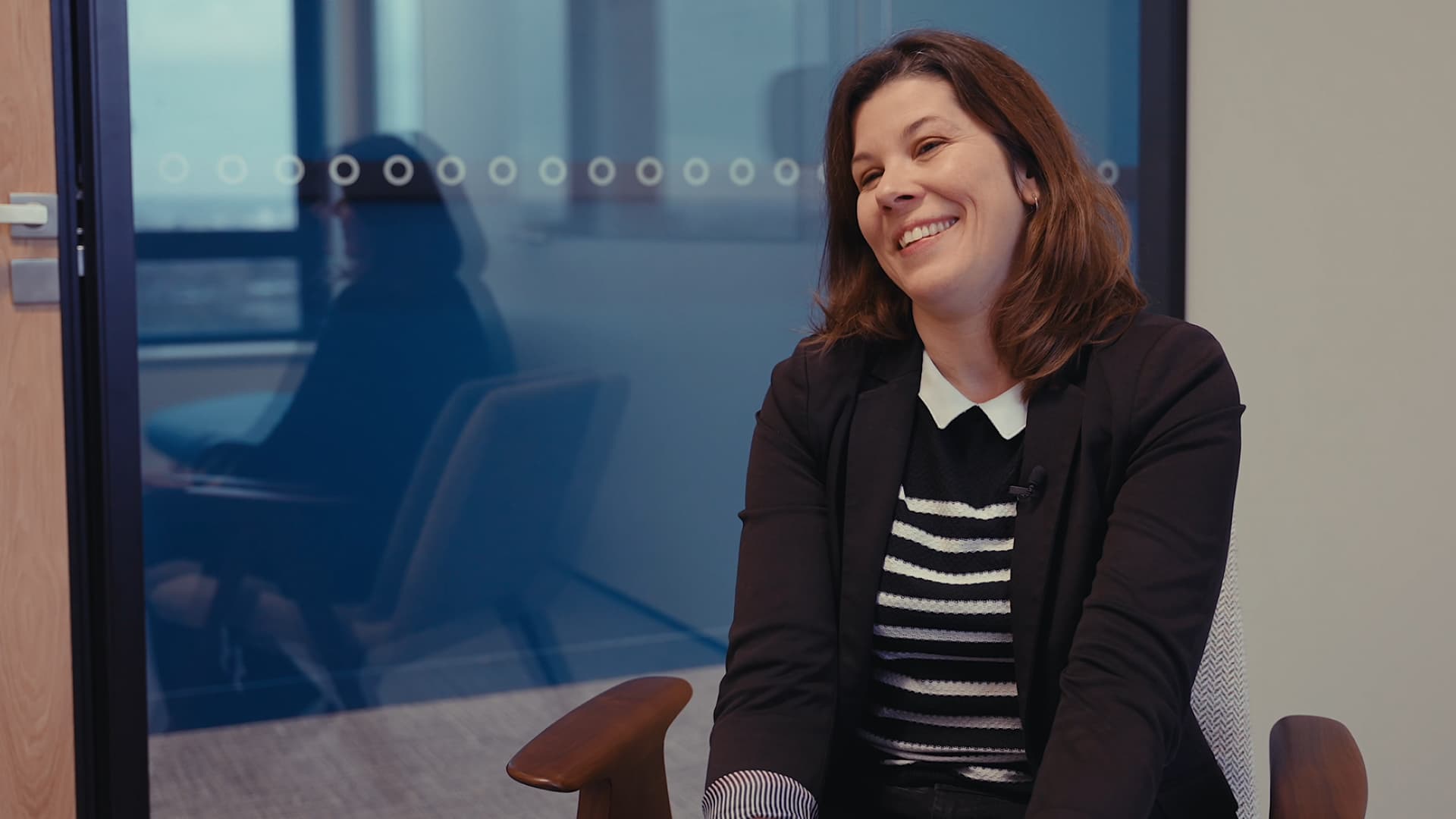 Femme souriante assise dans une salle de réunion moderne lors d'un entretien professionnel.