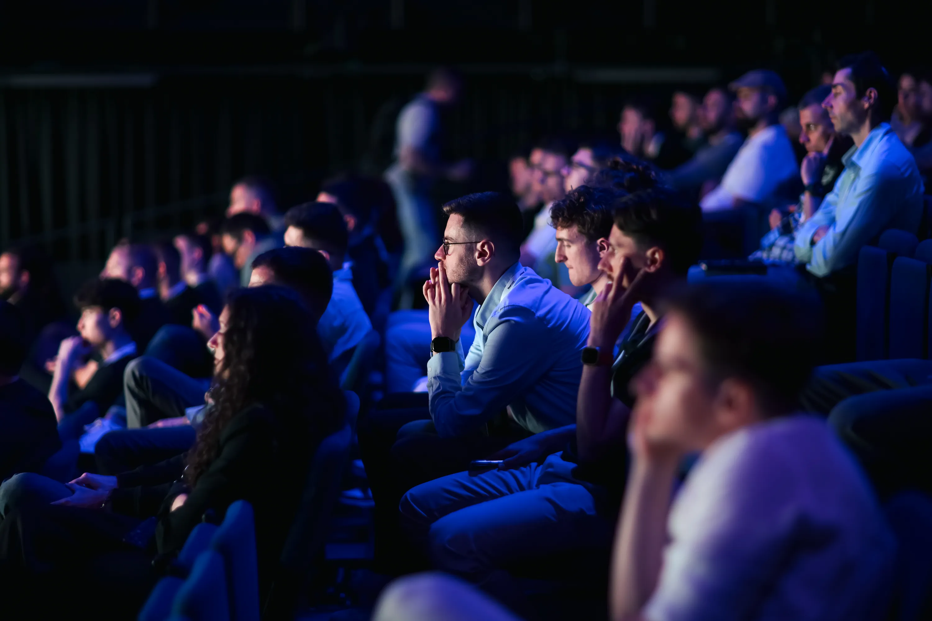 Audience attentive lors d’une conférence autour du web, du design et de l’IA, dans une ambiance immersive aux lumières bleues.