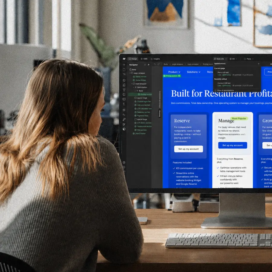 Collaboratrice travaillant sur l’optimisation d’un site Webflow sur un grand écran dans un bureau moderne, illustrant le développement web, le design d’interface et la gestion de contenu.