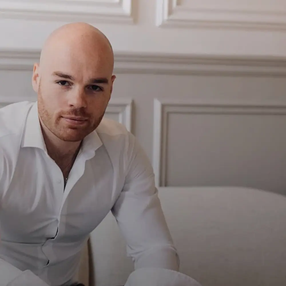 Portrait d’un dirigeant en chemise blanche dans un bureau élégant, illustrant le leadership, le conseil stratégique et l’accompagnement des entreprises.