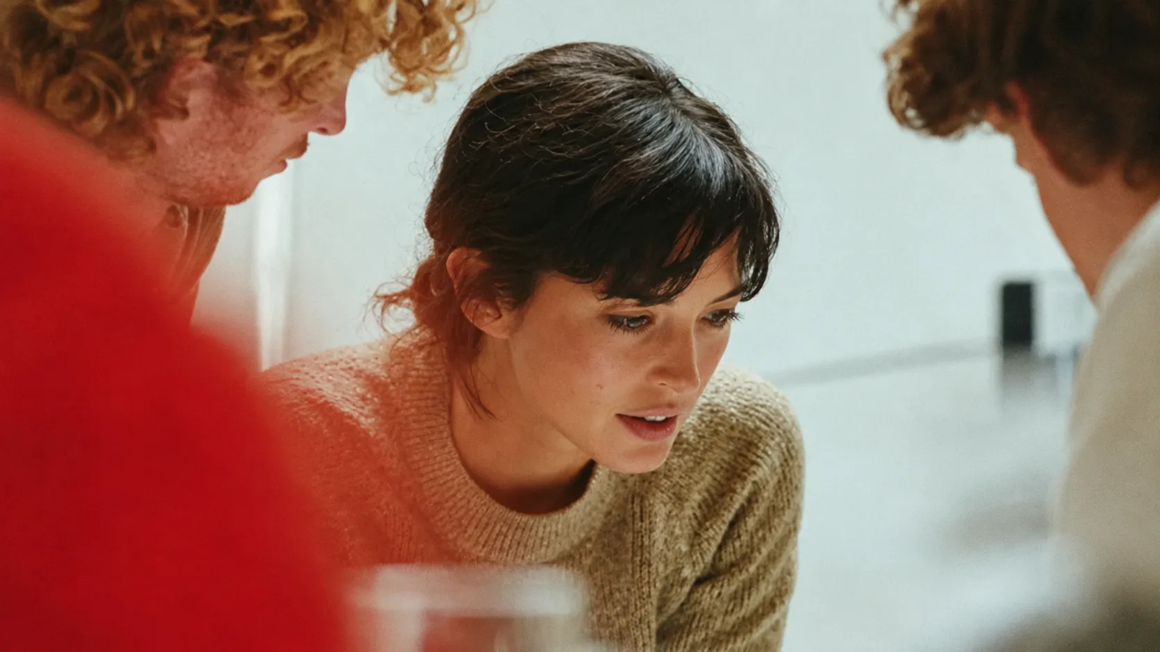 Équipe réunie autour d’une table de travail, avec un collaborateur concentré au centre lors d’un échange collectif.