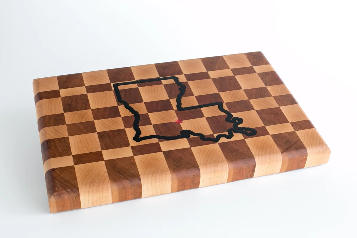 A modern kitchen with mint green cabinets, white countertops, and island and two wooden stools.