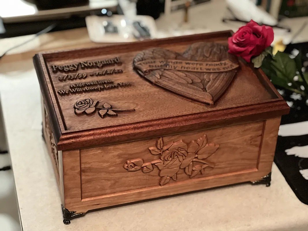 A hardwood keepsake box with a three-dimensional relief carved lid of roses and a heart.