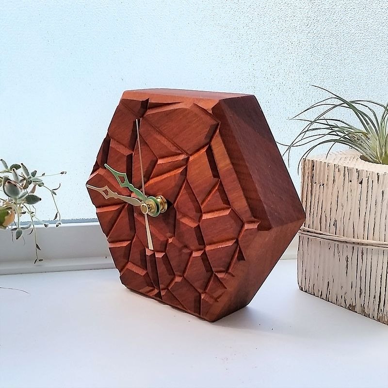 A faceted red wooden clock with an irregular cell pattern across its face.