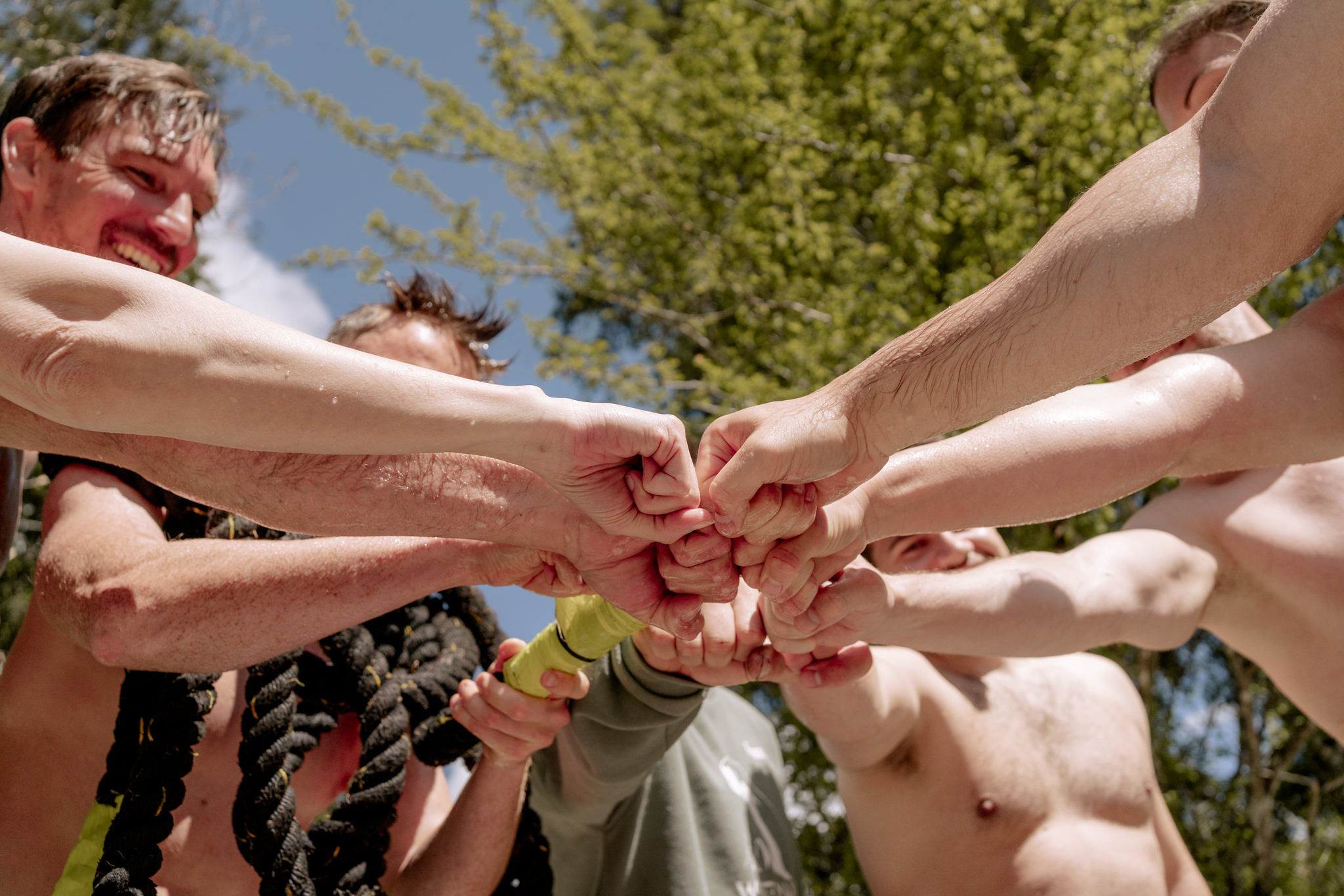 Die Teilnehmer halten alle ihre Fäuste in der Mitte zusammen und freuen sich