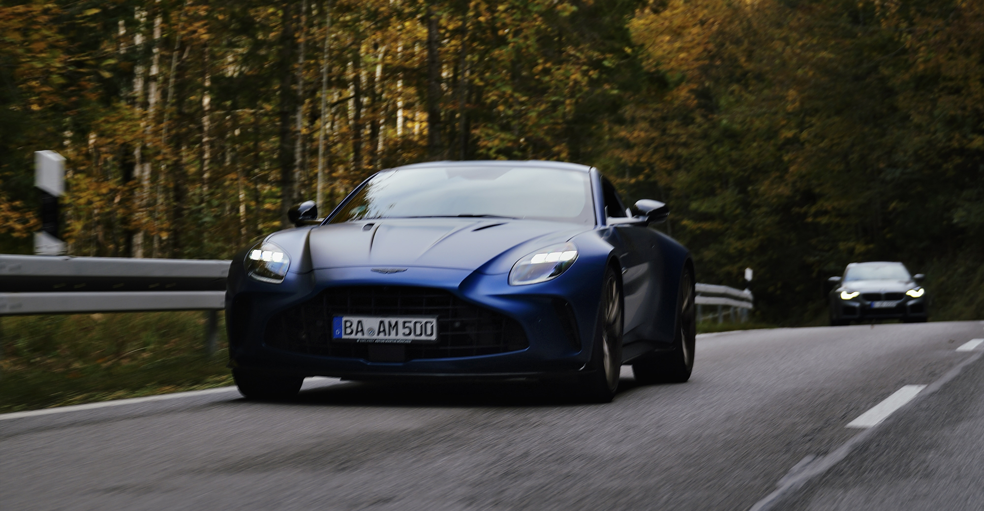 Ein Aston Martin gefolgt von einem BMW M auf einer Sportwagen-Ausfahrt im wunderschönen Herbst.