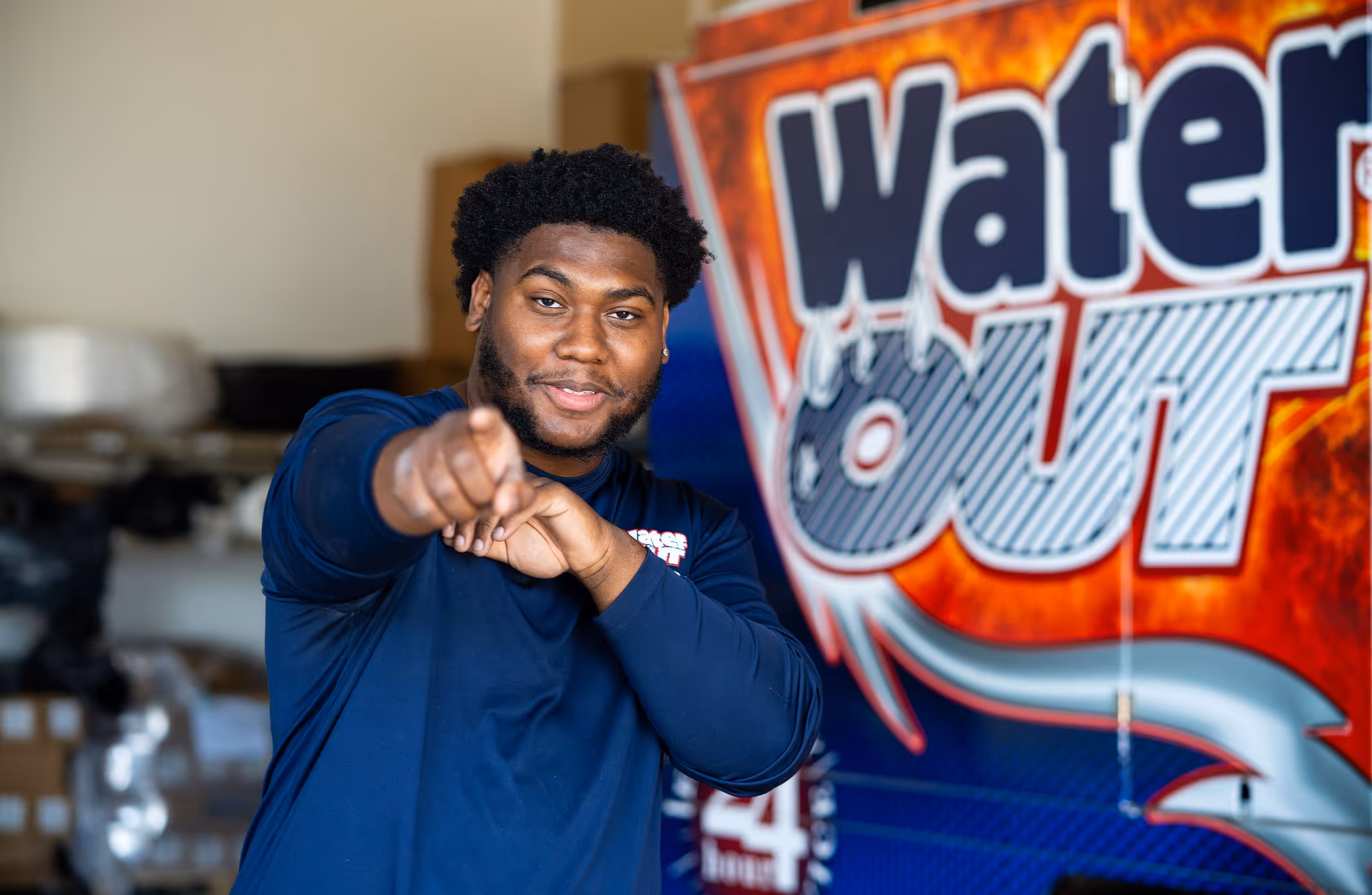 A person next to the water out logo smiles and points at the camera