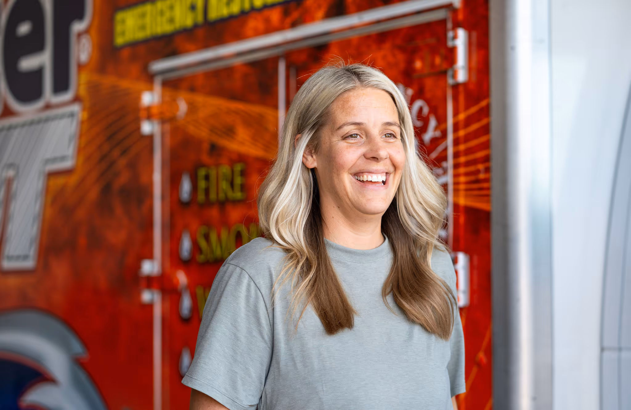 A person laughs and smiles in front of a red work truck.